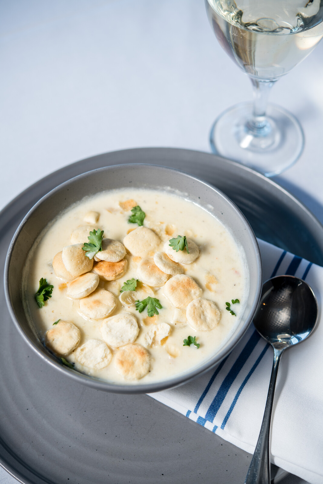 a bowl of soup with crackers and parsley on a plate