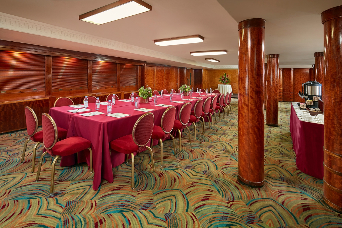 a long table with red cloth and chairs in a room