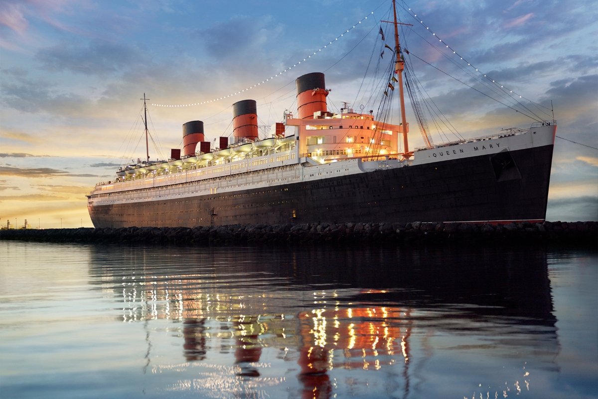 a large ship on a dock with RMS Queen Mary in the background