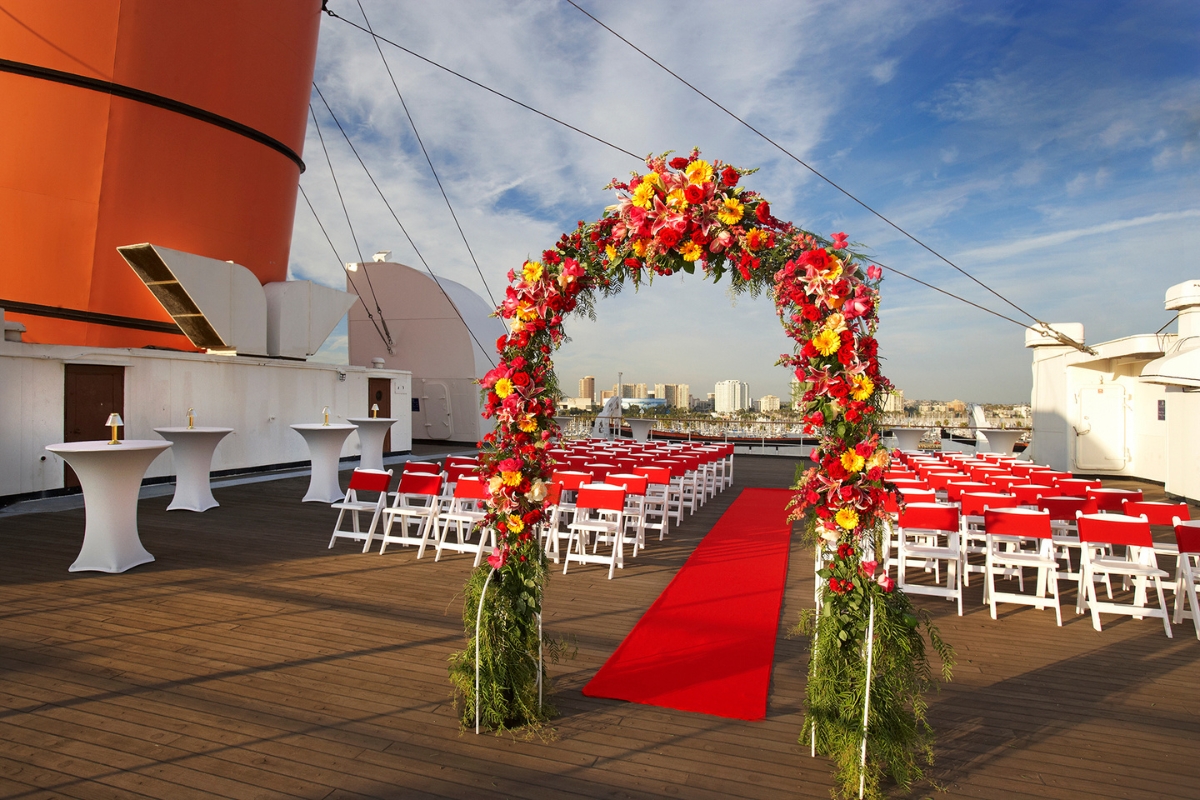 a wedding ceremony on a deck with chairs and a red carpet
