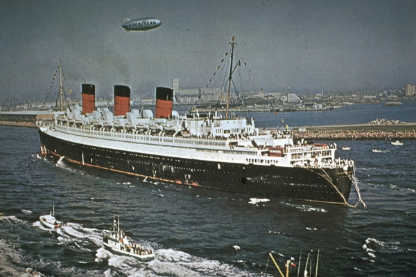 a large ship in the water with RMS Queen Mary in the background