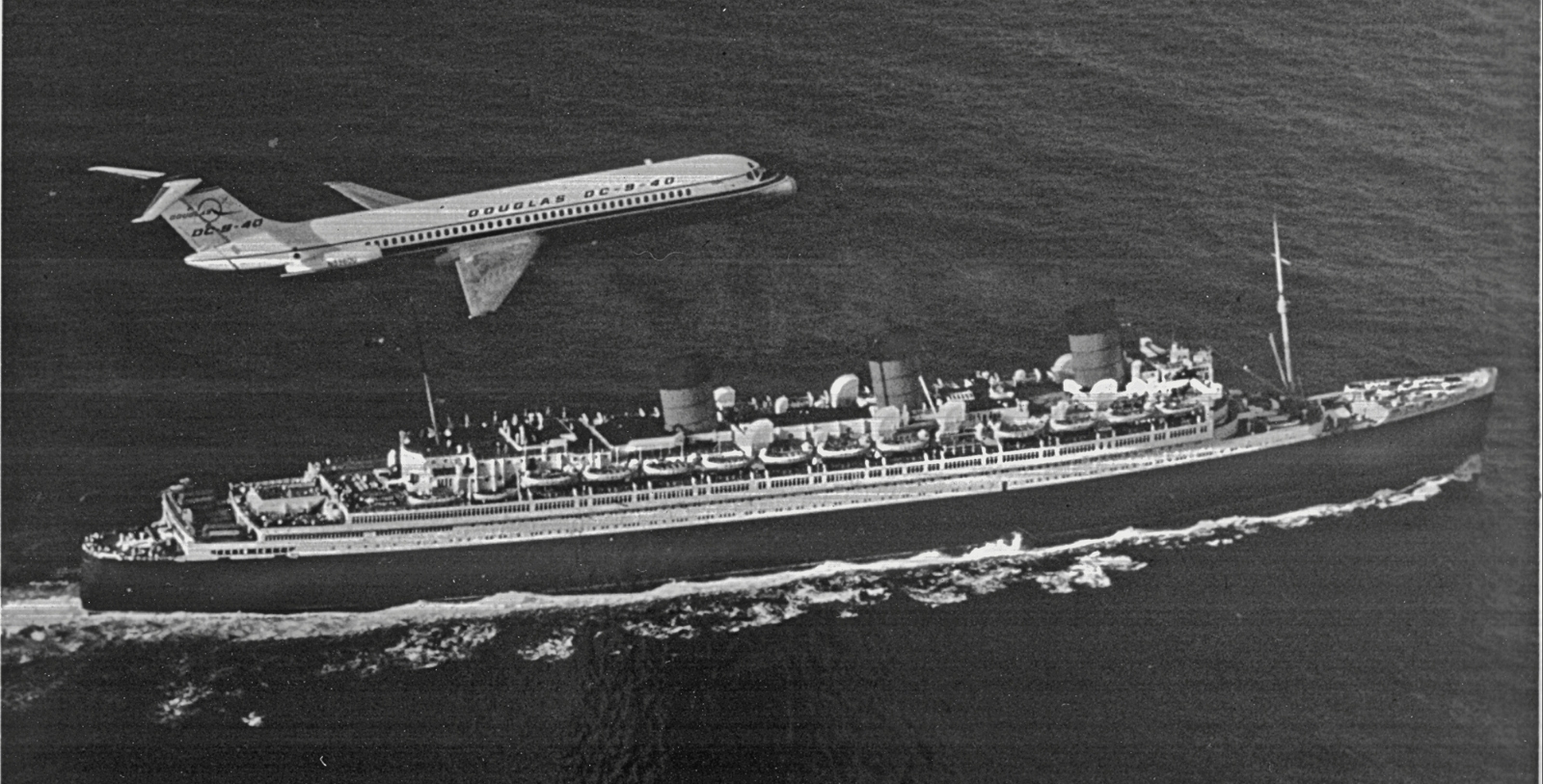 an airplane flying over a large ship