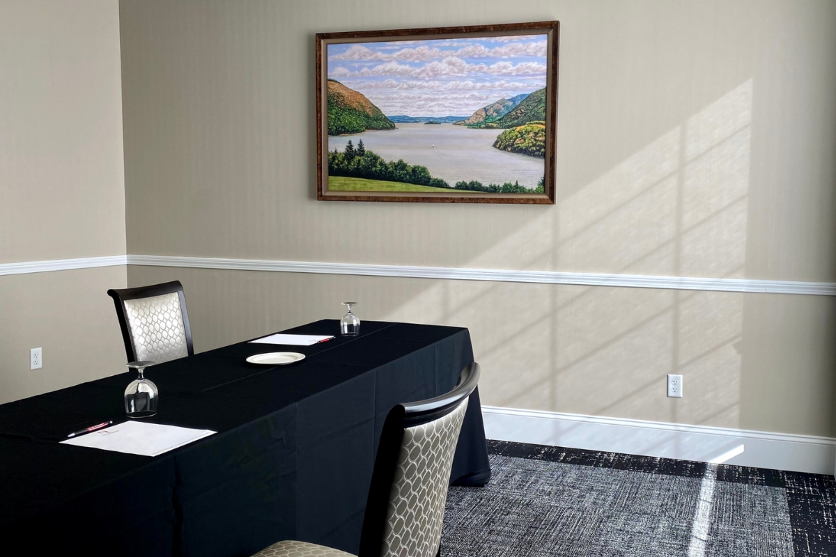 a table with a black tablecloth and chairs in a room with a painting on the wall