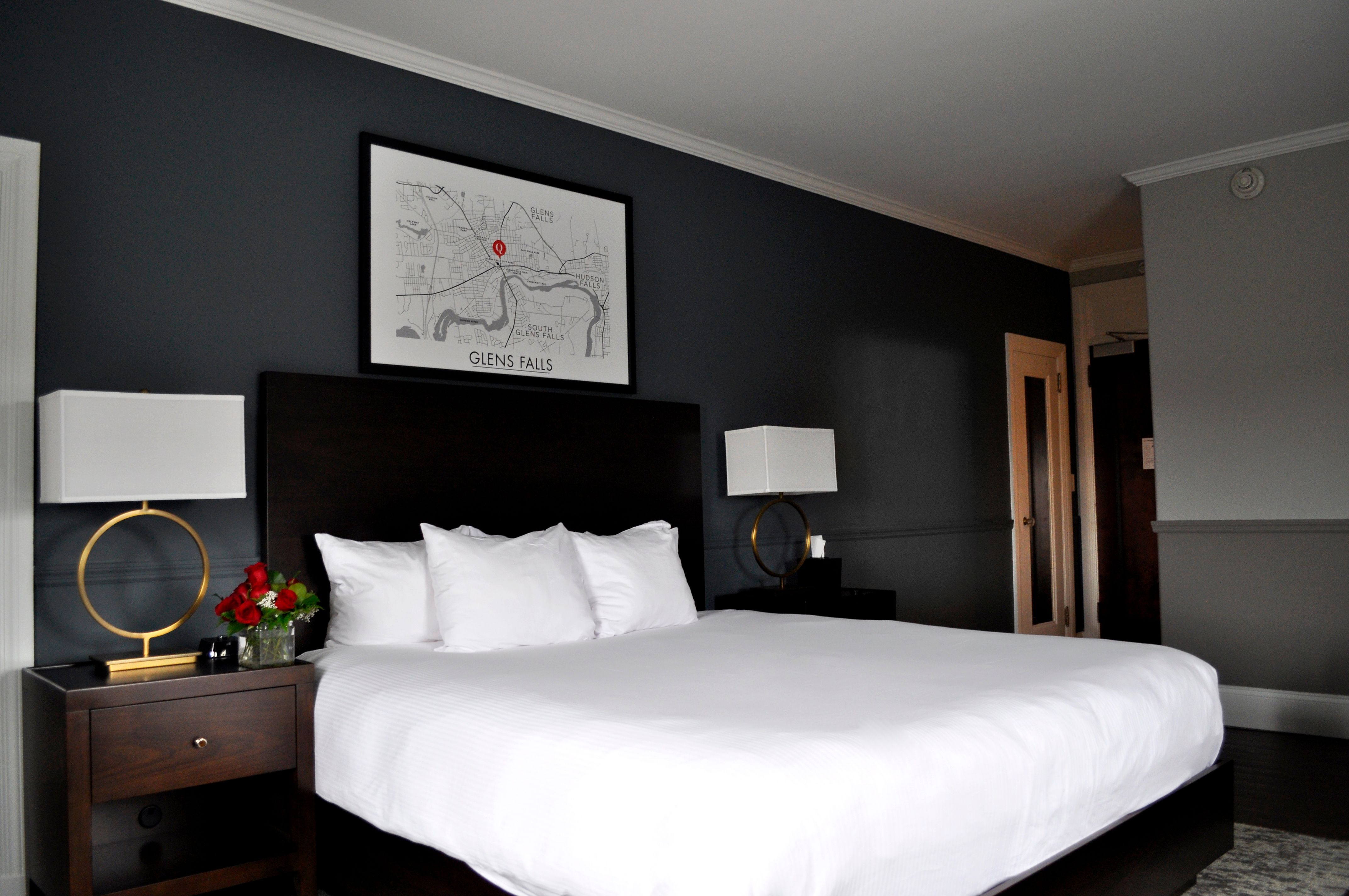 a bed with white sheets and a lamp on a table