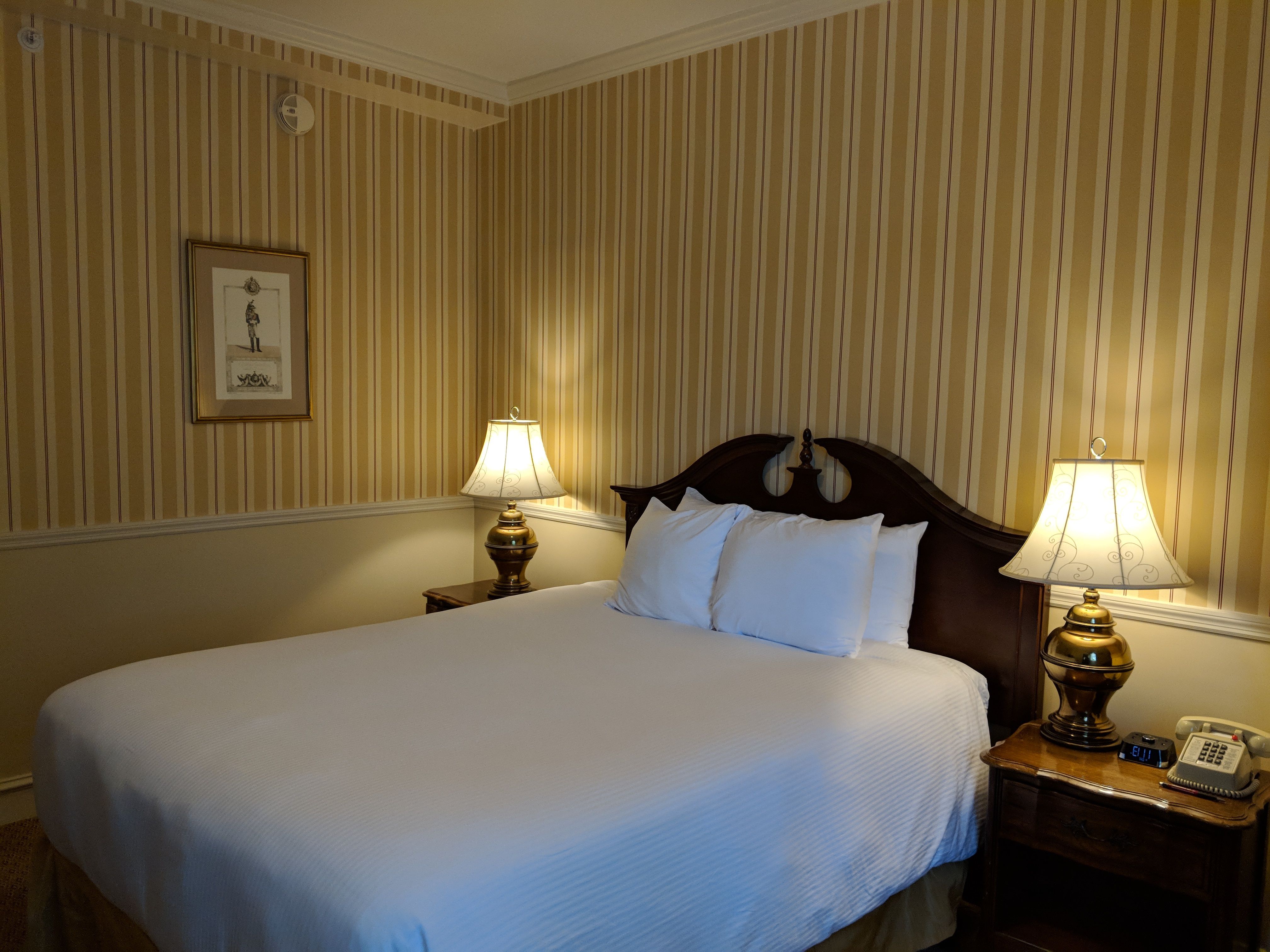 a bed with white sheets and lamps in a room