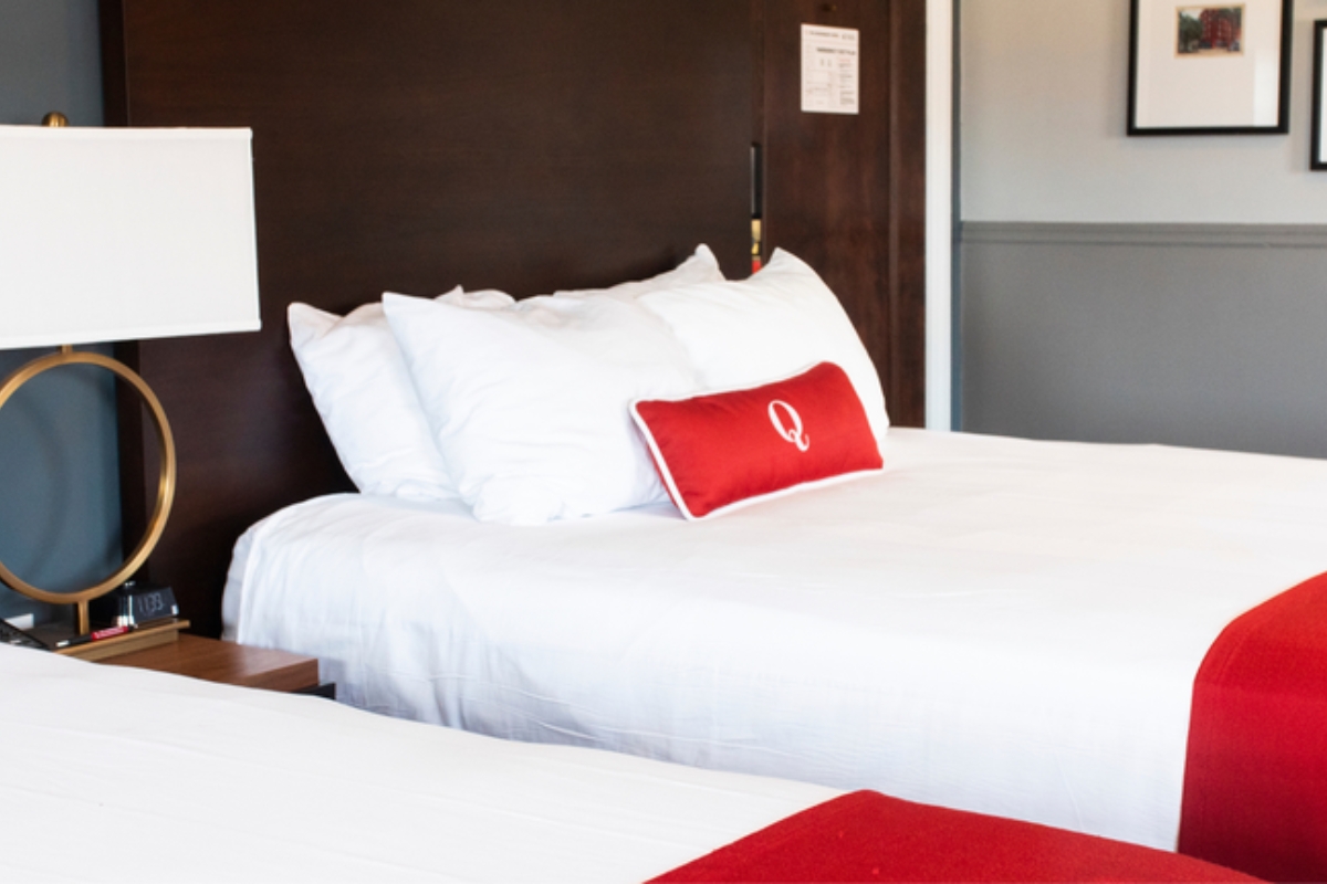 a bed with white sheets and red pillow