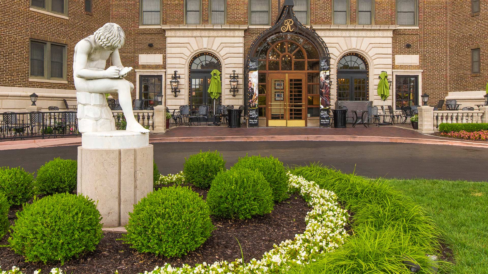 a statue of a boy holding a book in front of a building
