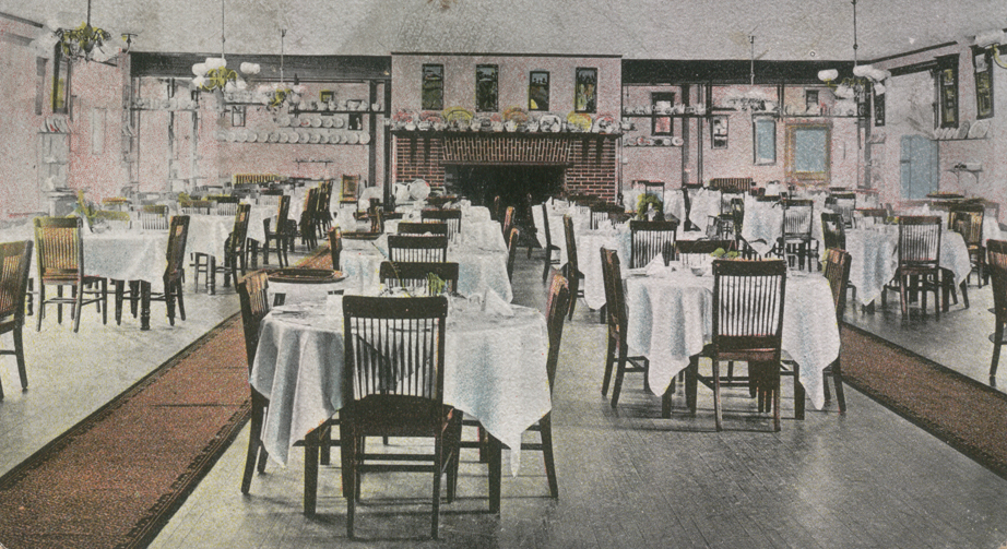 Vintage colorized illustration of a large historic dining hall filled with round and rectangular tables set with white tablecloths, dark wooden chairs, a brick fireplace, and decorative plates lining the walls.