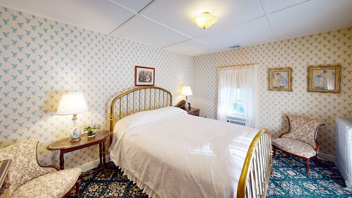 a bed with a gold headboard and a lamp on a blue carpet
