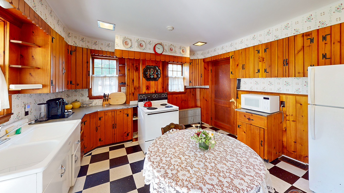a kitchen with wood paneling and a table with a white stove and a white oven