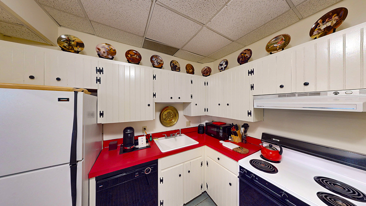 a kitchen with white cabinets and red counter tops