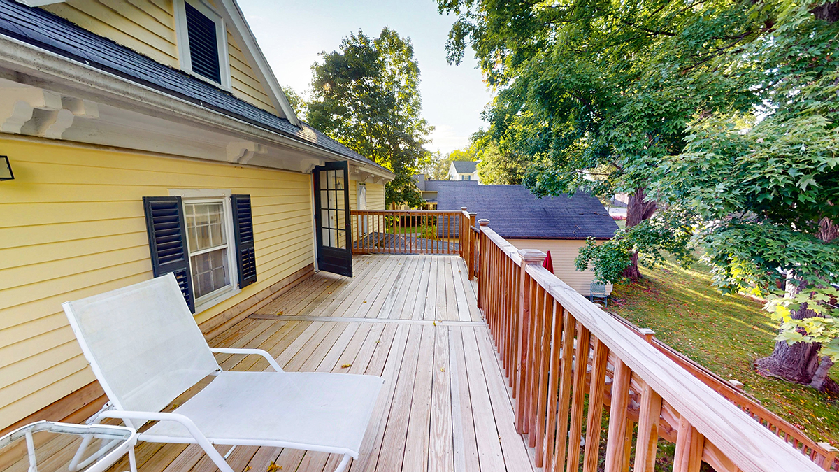 a deck with chairs and a railing on a house