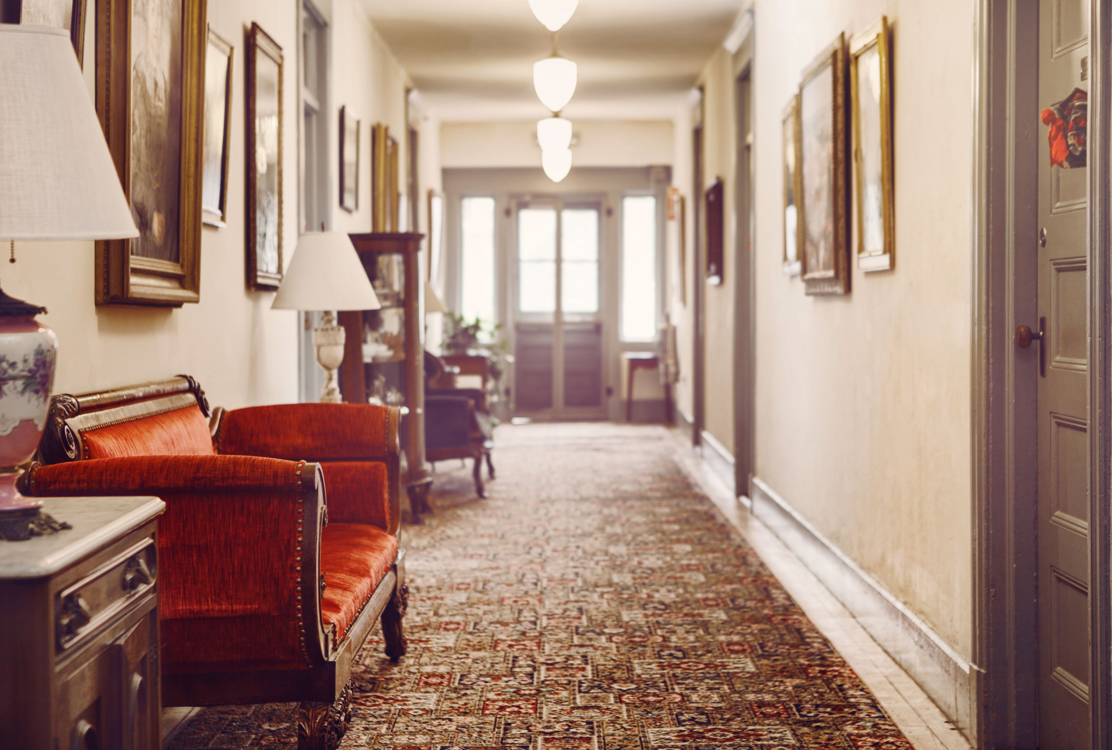 a hallway with a red couch and a lamp