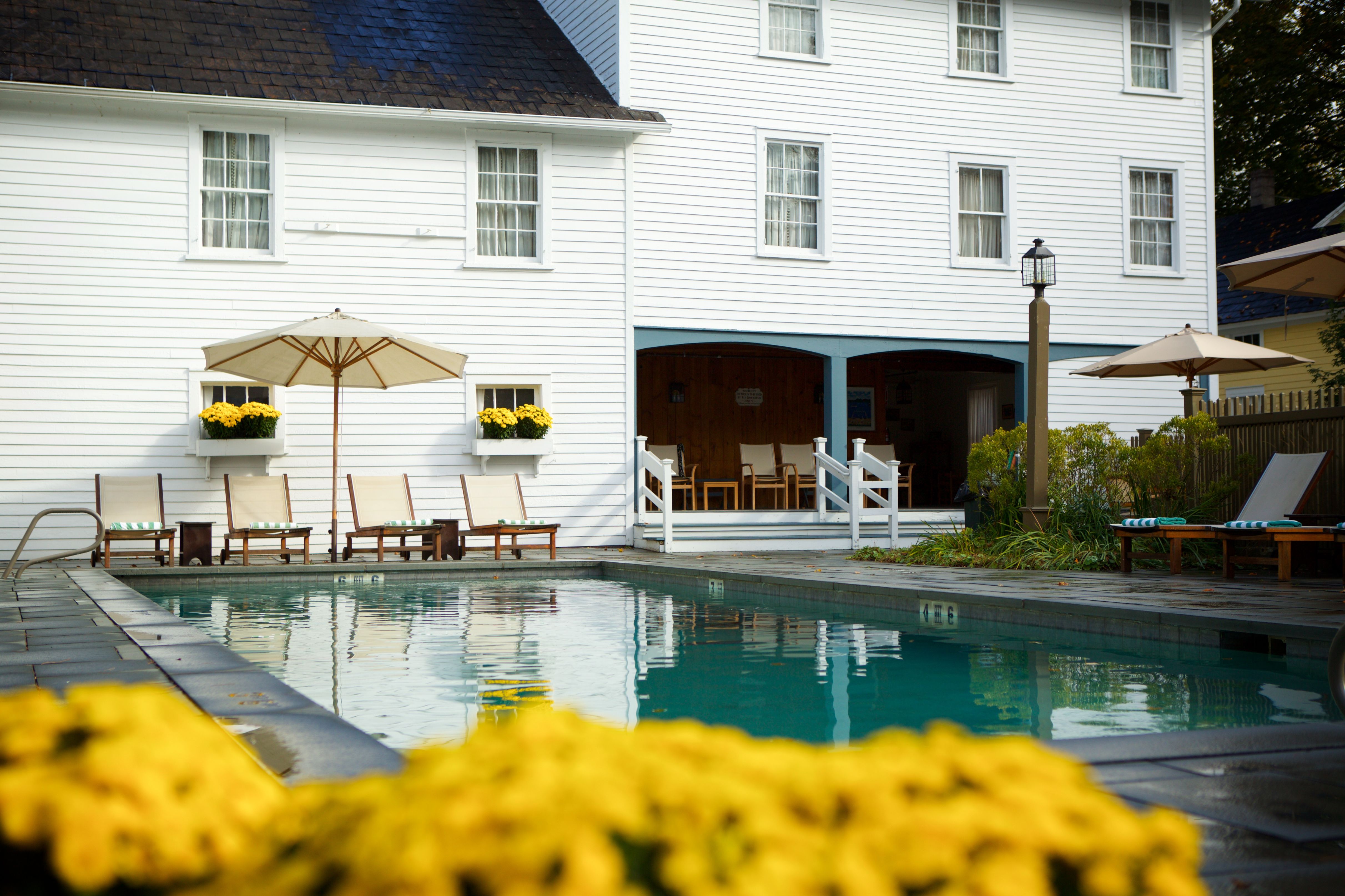 a pool with chairs and umbrella in front of a white building