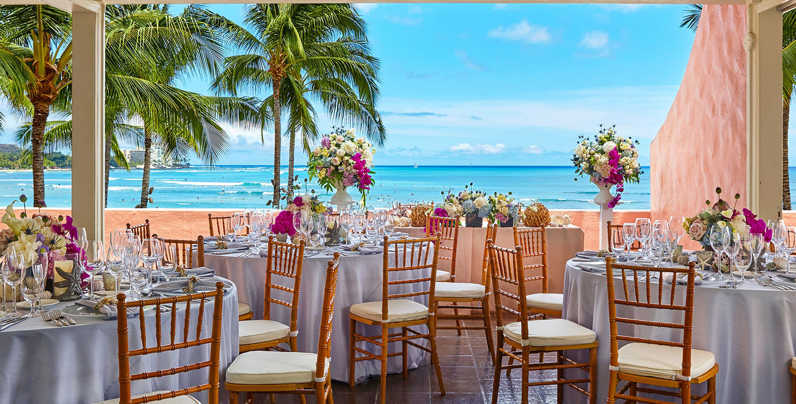 a table set up with flowers and chairs on a beach