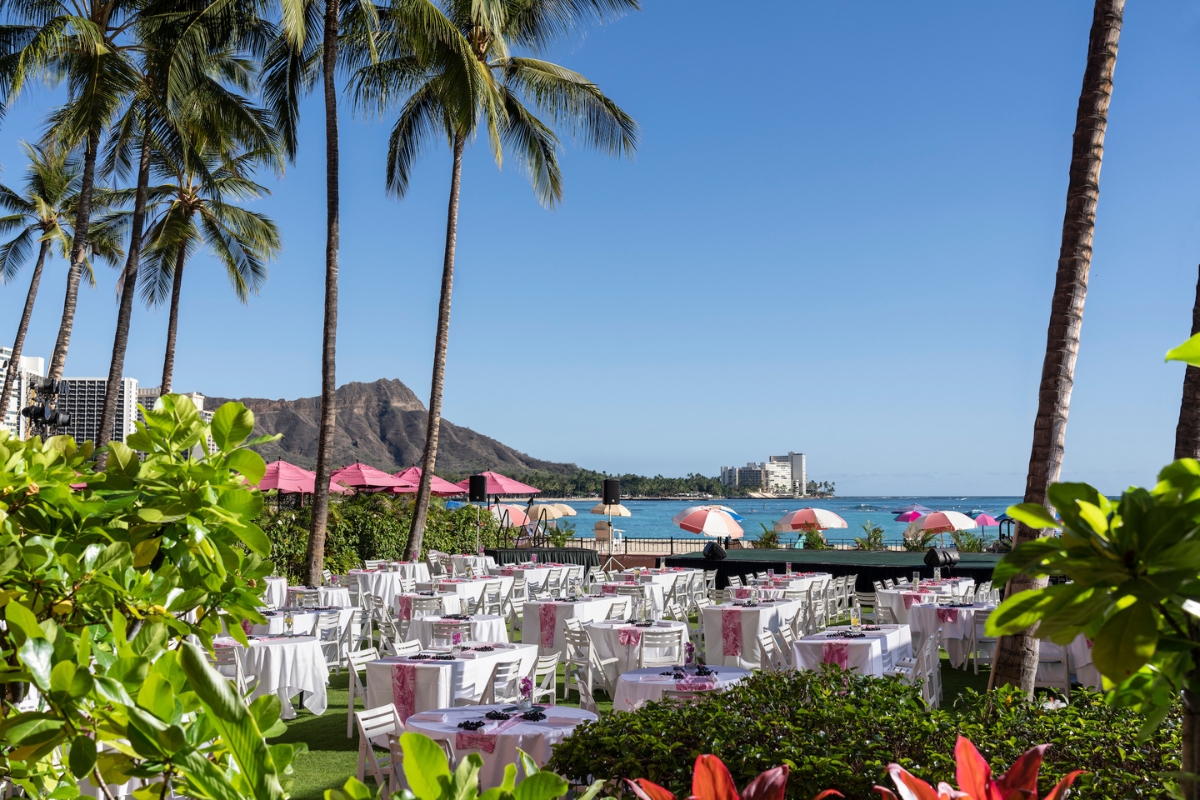 a group of tables and chairs with pink umbrellas and palm trees
