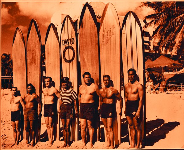 a group of men standing in front of surfboards