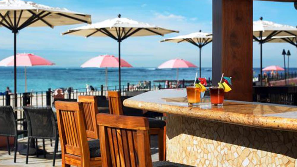 a table with drinks on it and chairs on the beach