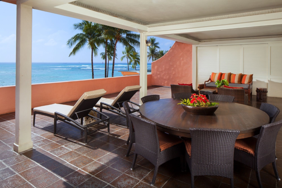 a patio with a table and chairs on a deck overlooking the ocean