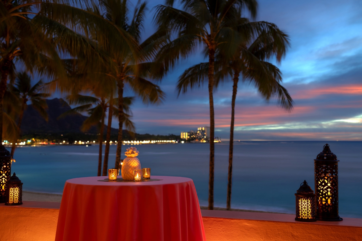 a table with candles on it and palm trees in the background