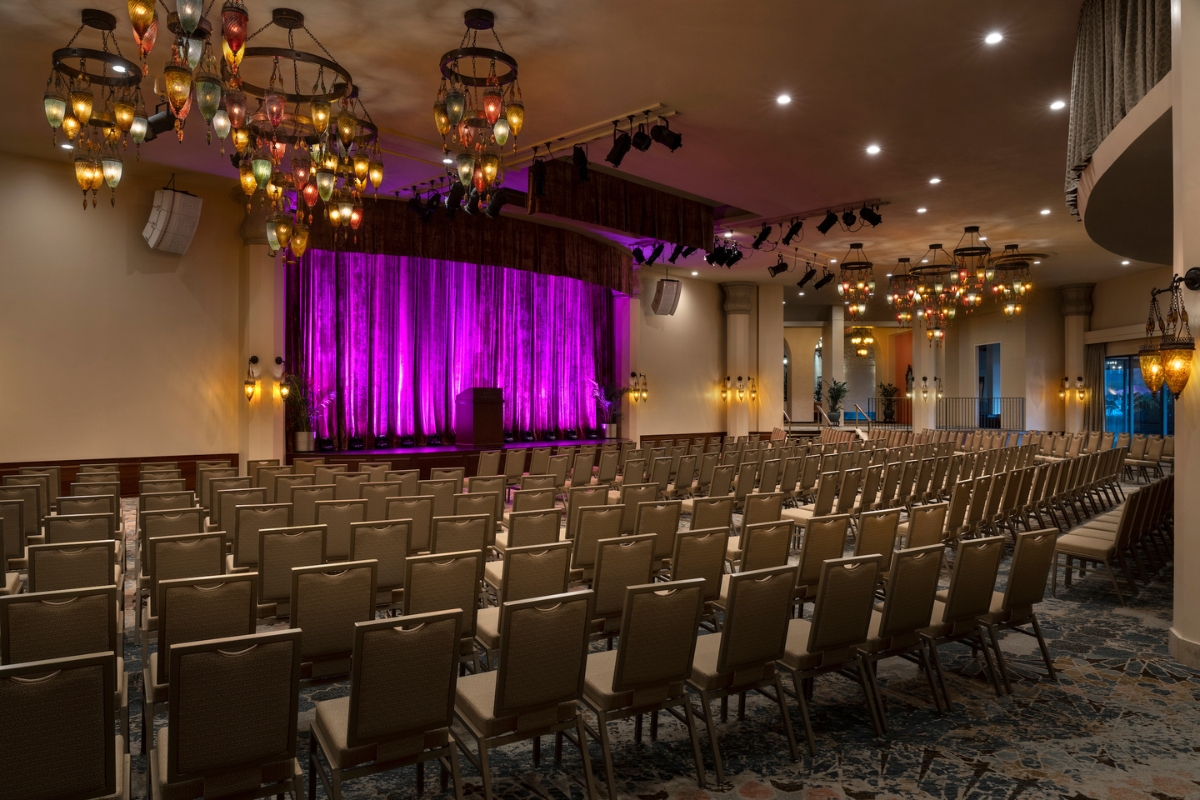 a room with rows of chairs and purple curtain