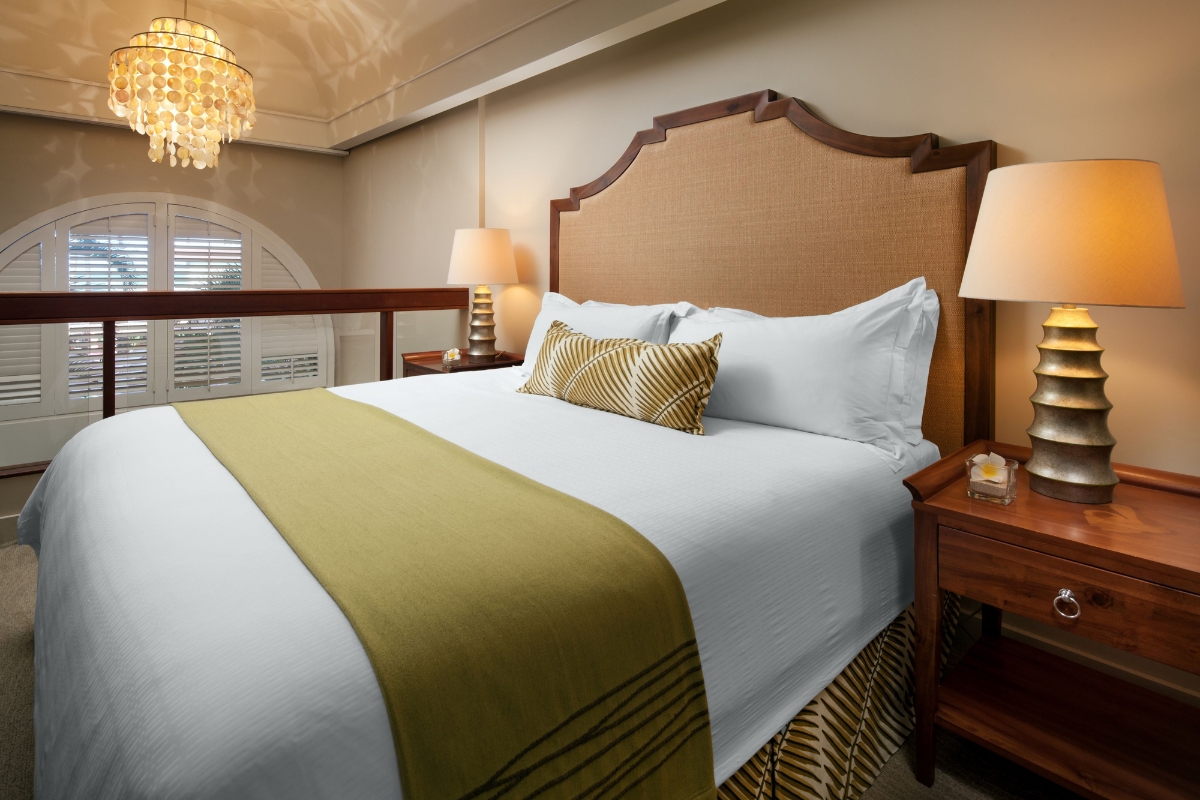 a bed with a green blanket and a lamp