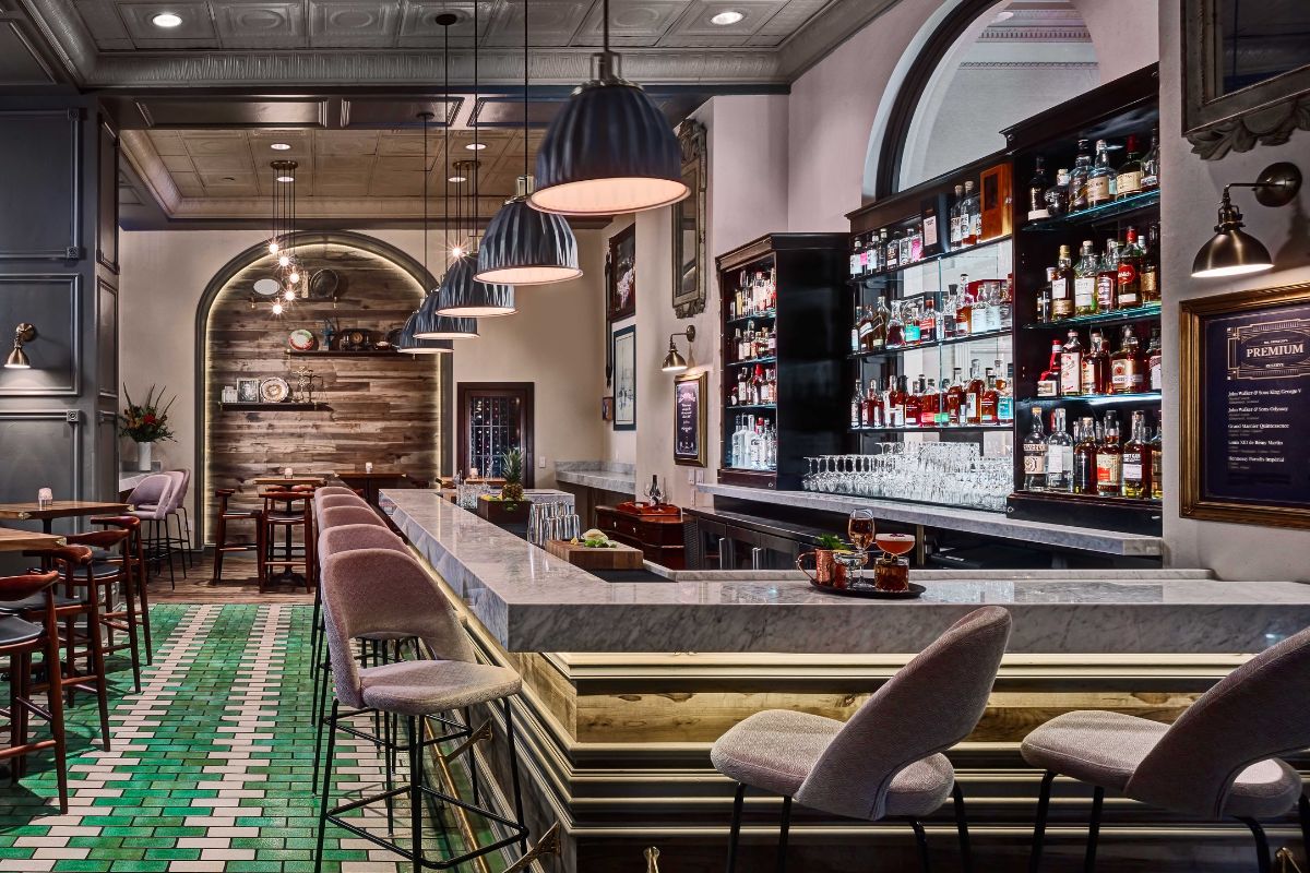 a bar with shelves of liquor and chairs