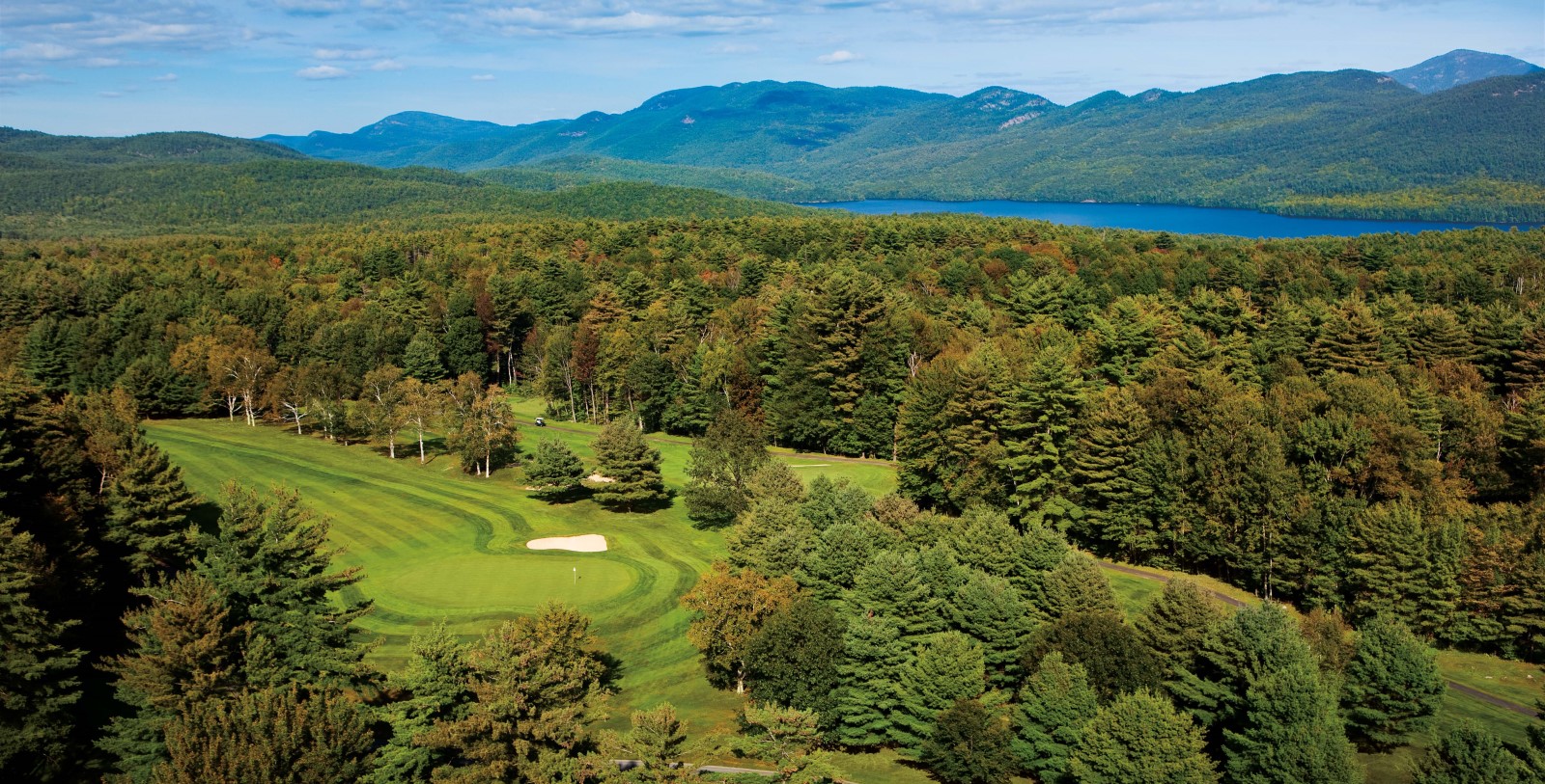 a golf course with trees and mountains in the background