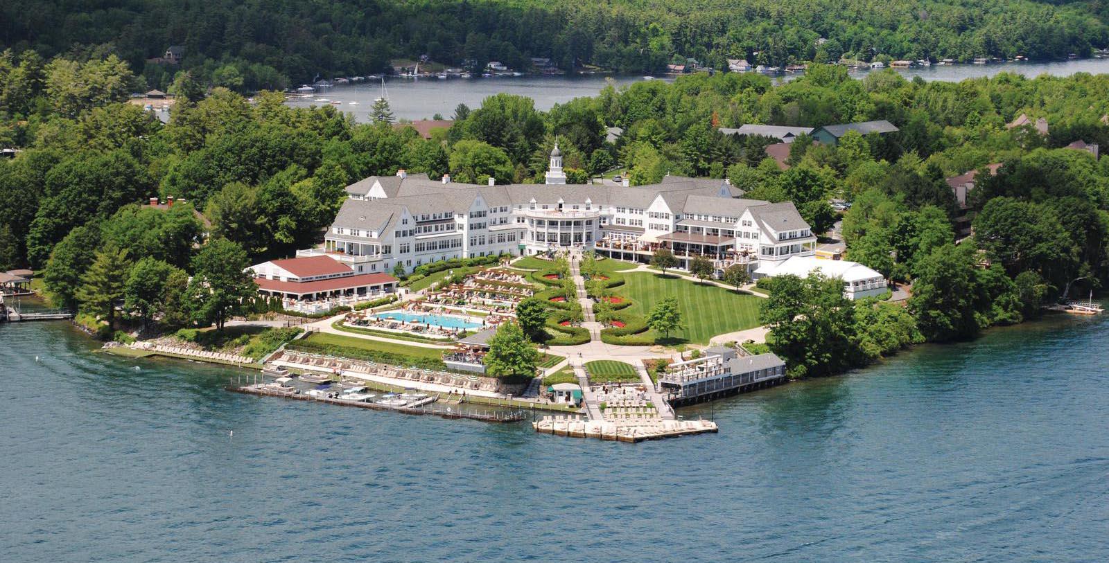a large white building with a large lawn and a pool surrounded by water