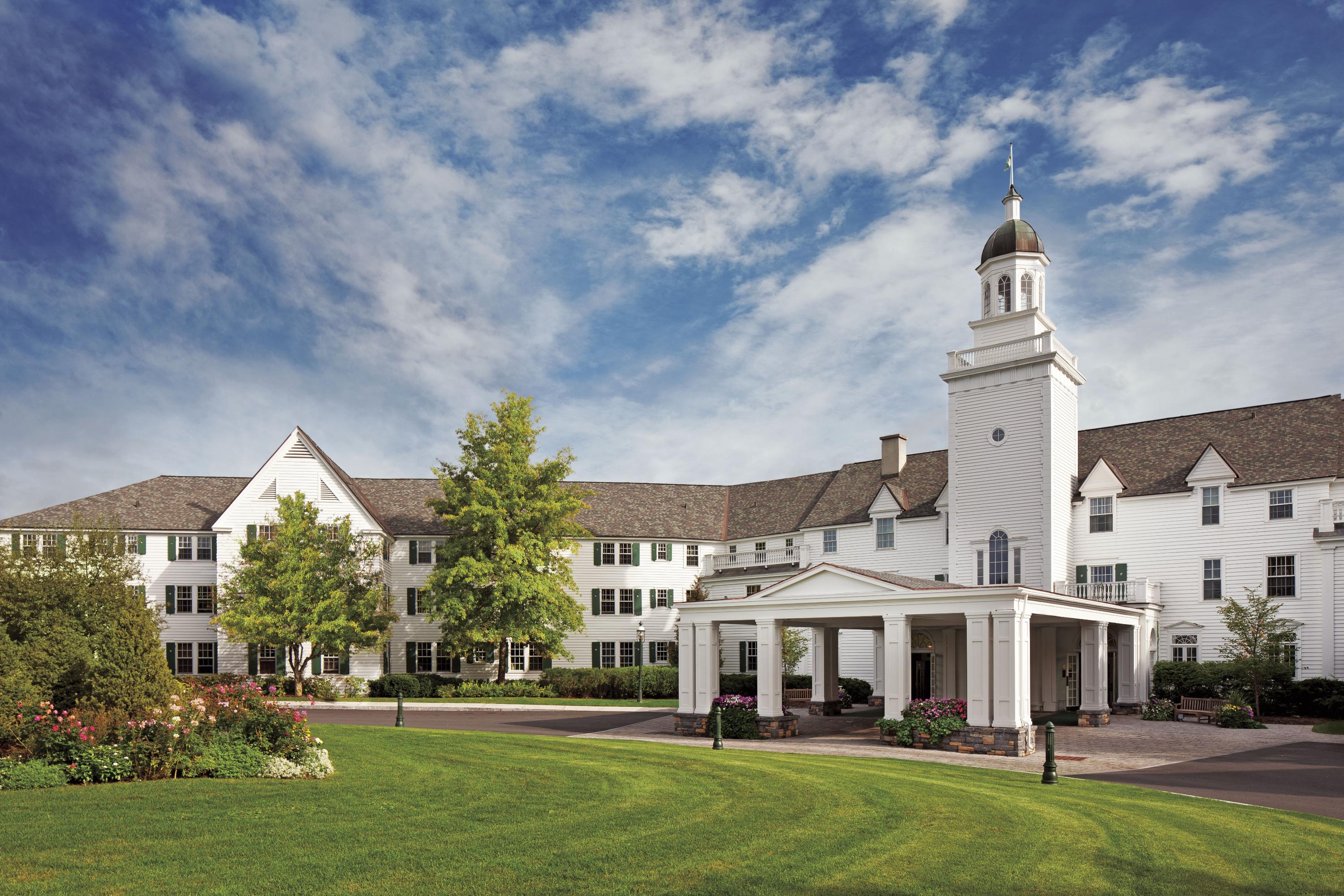 a large white building with a tower and a lawn