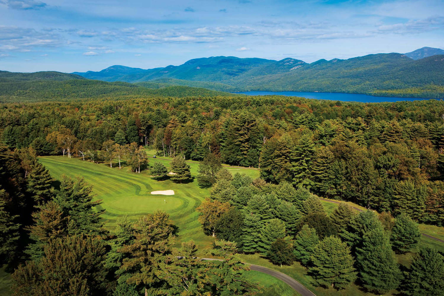 a golf course with a lake and mountains in the background