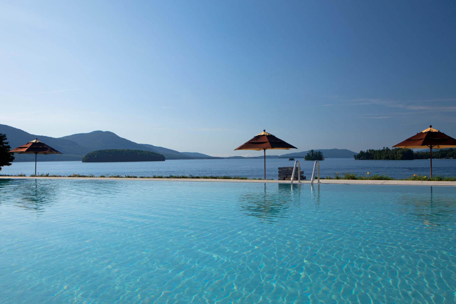 a pool with a umbrella and a chair on the side