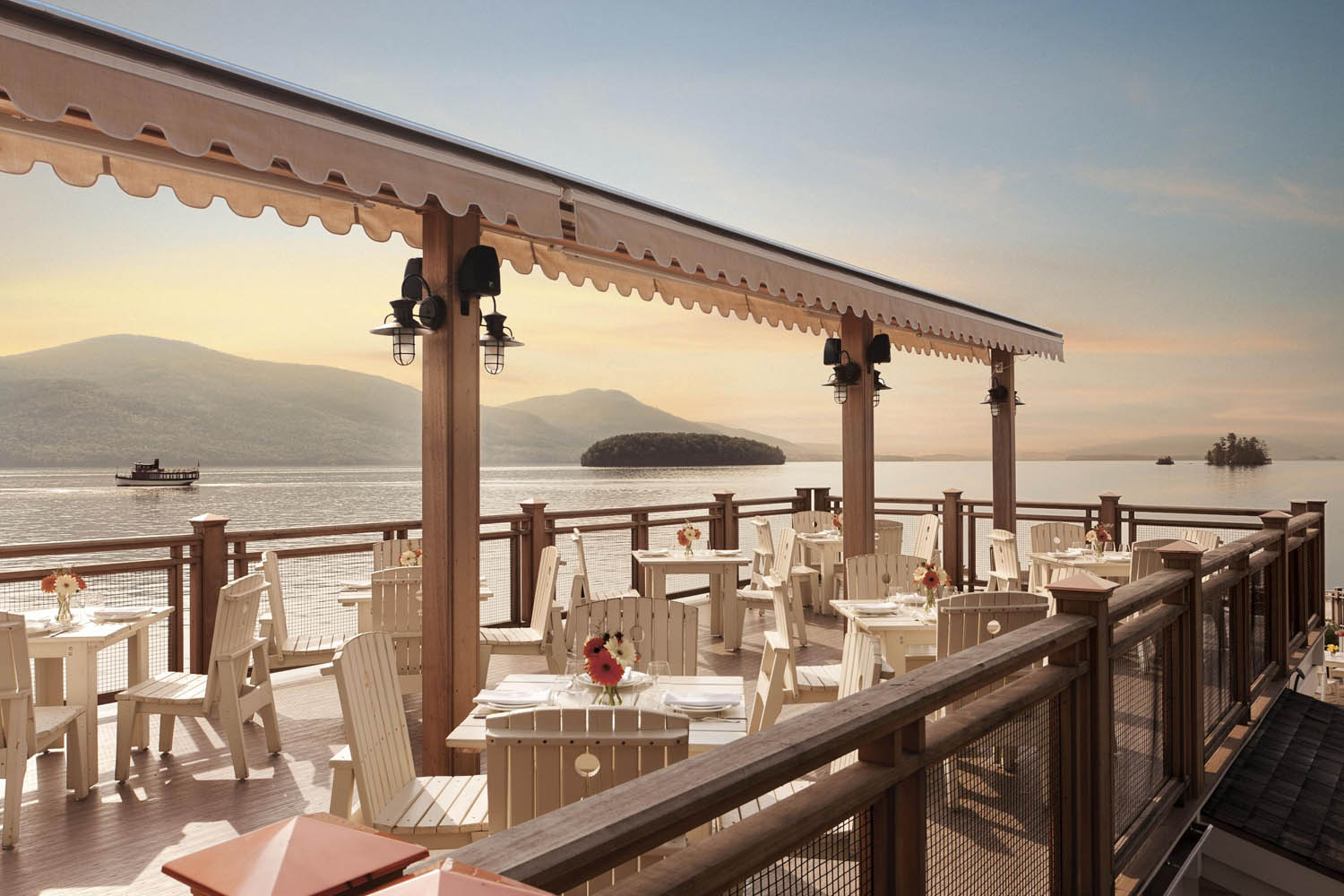 a restaurant with tables and chairs on a deck overlooking a body of water