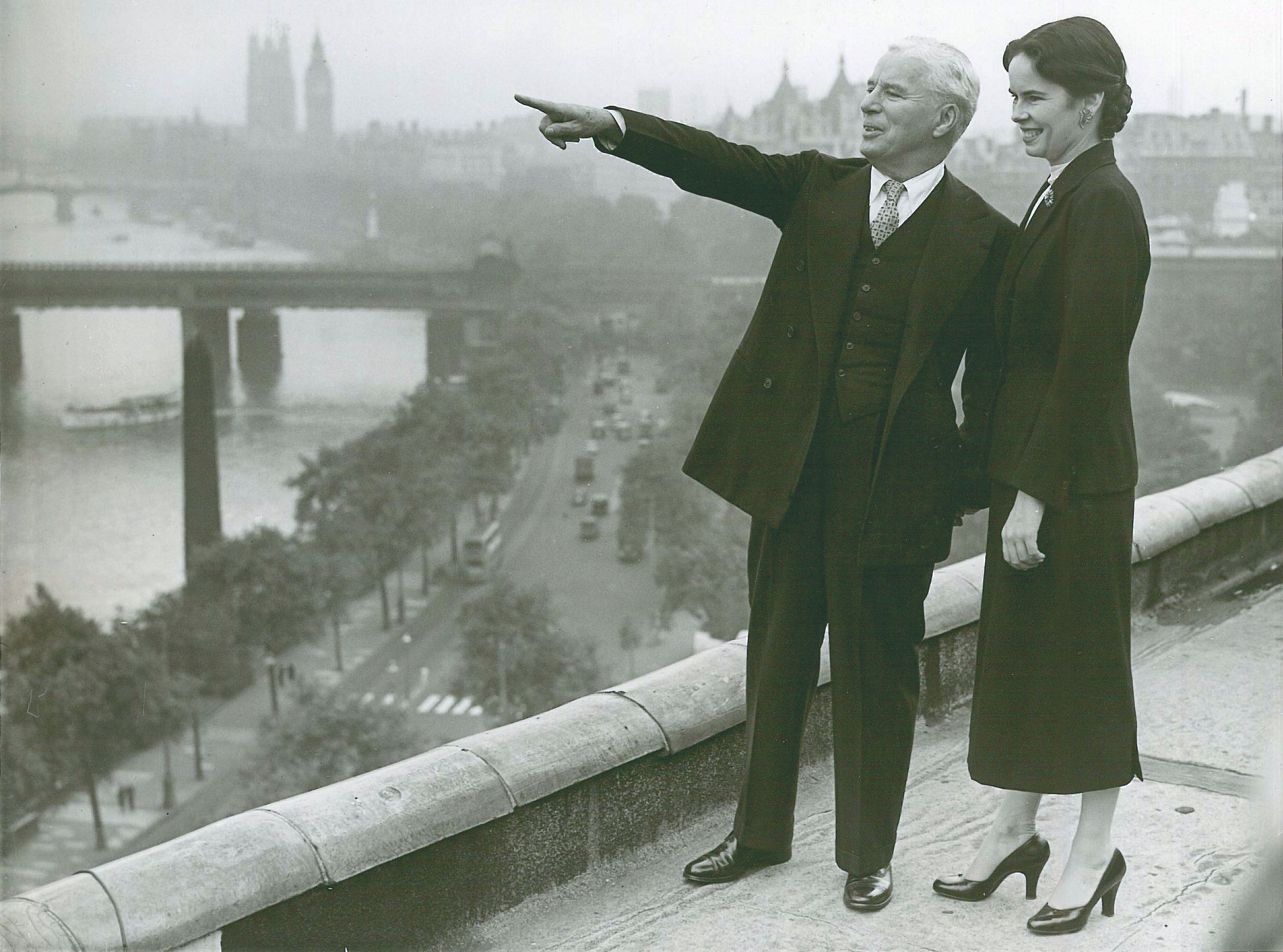 a man and woman standing on a ledge pointing