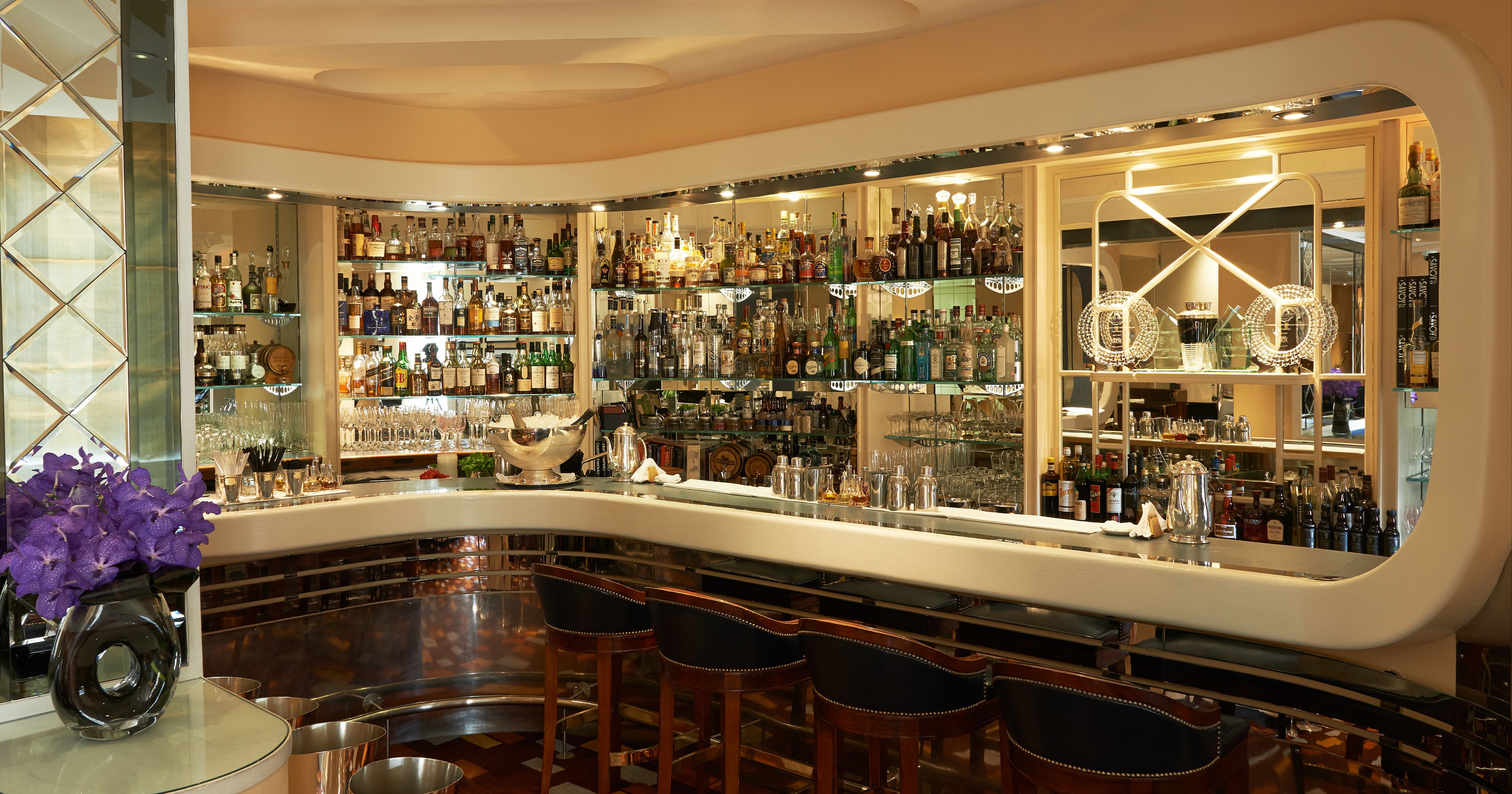 a bar with shelves of liquor and chairs