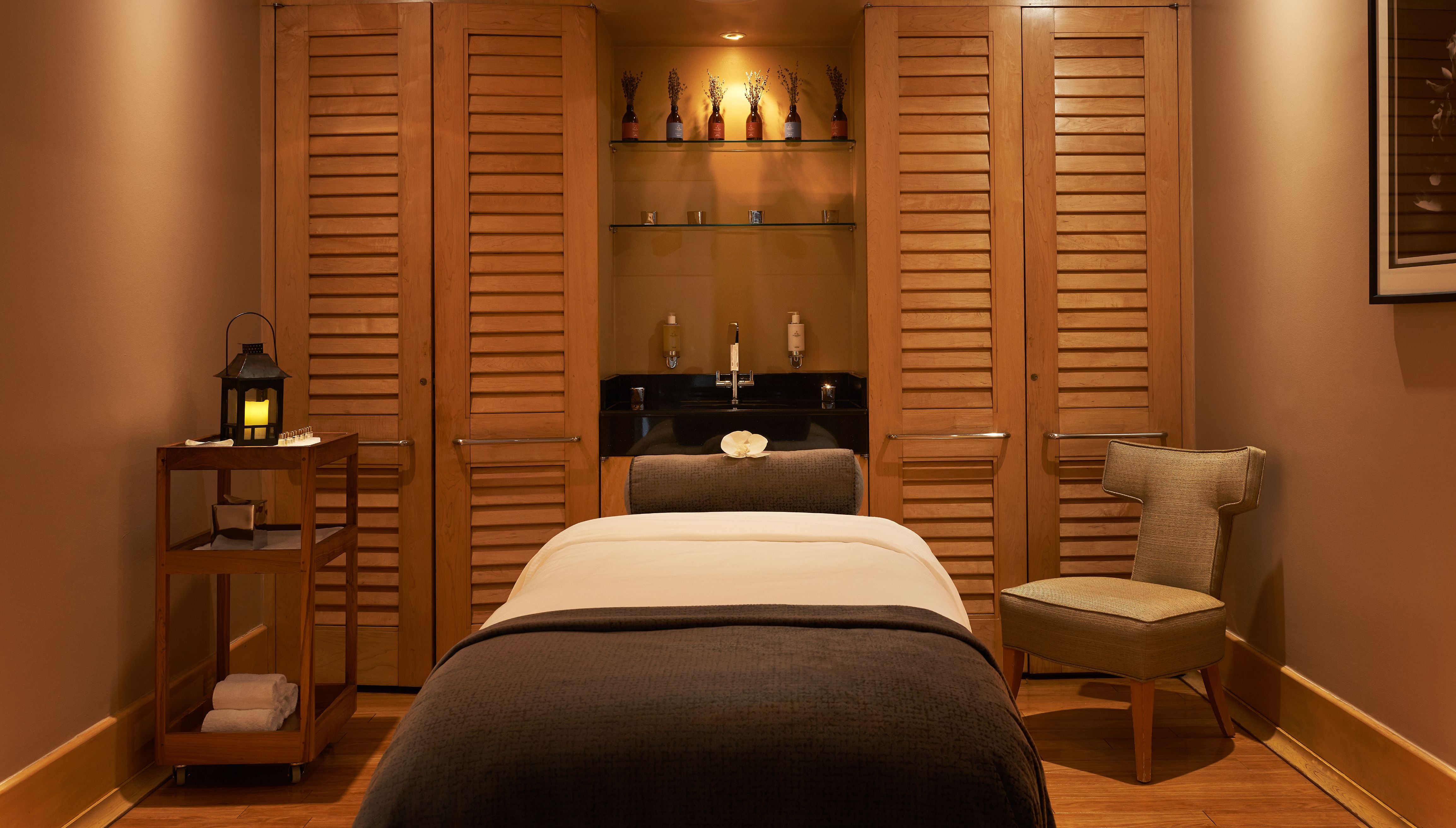 a massage room with a bed and a sink