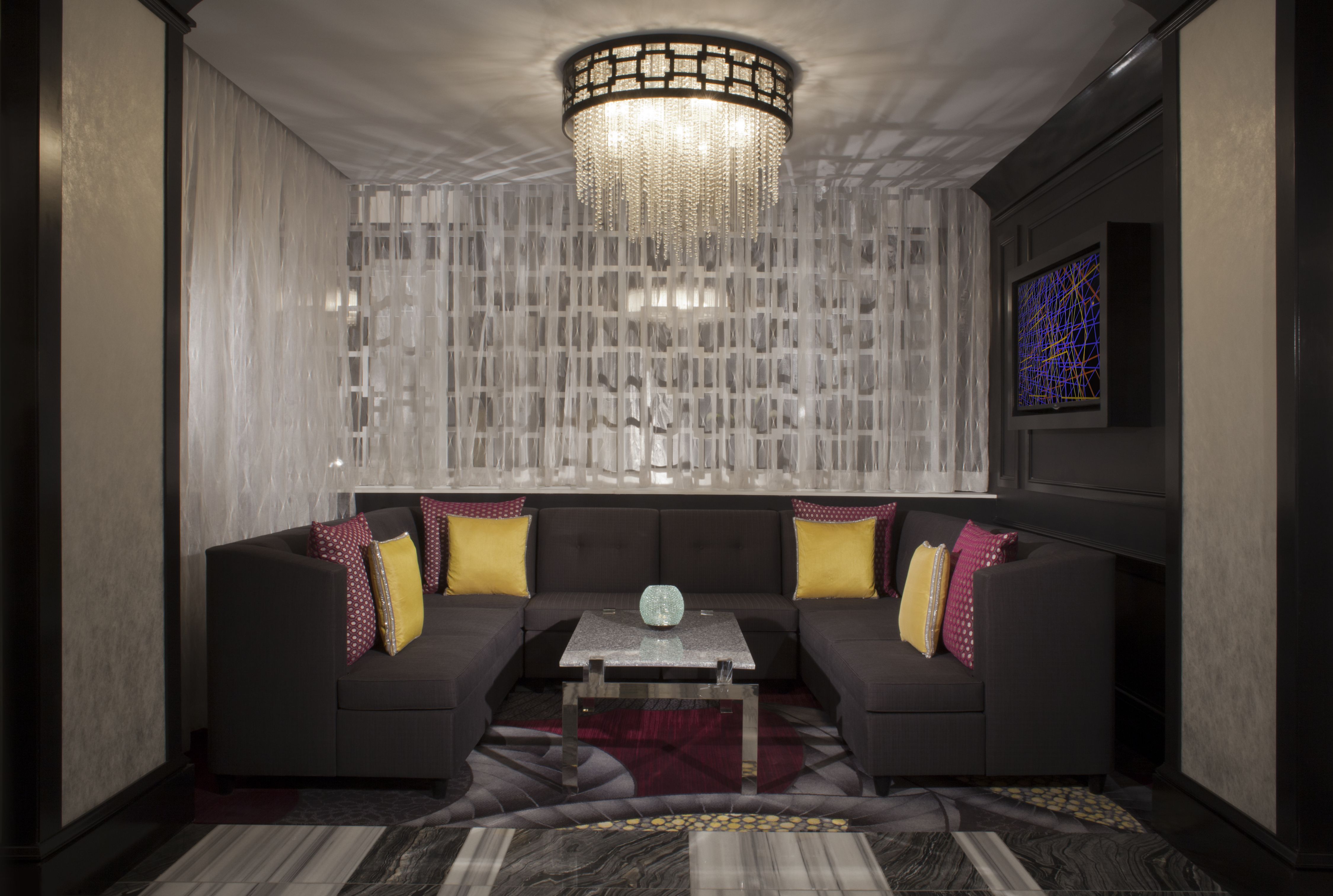 a couch with yellow and red pillows in a room with a chandelier