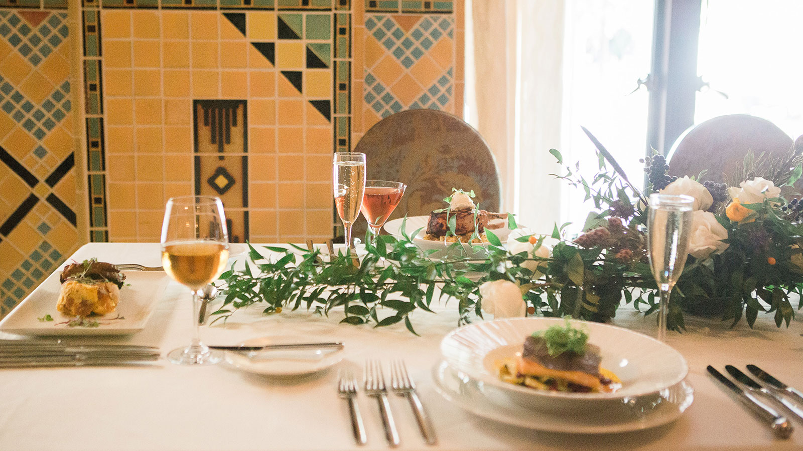 a table with plates of food and glasses of wine