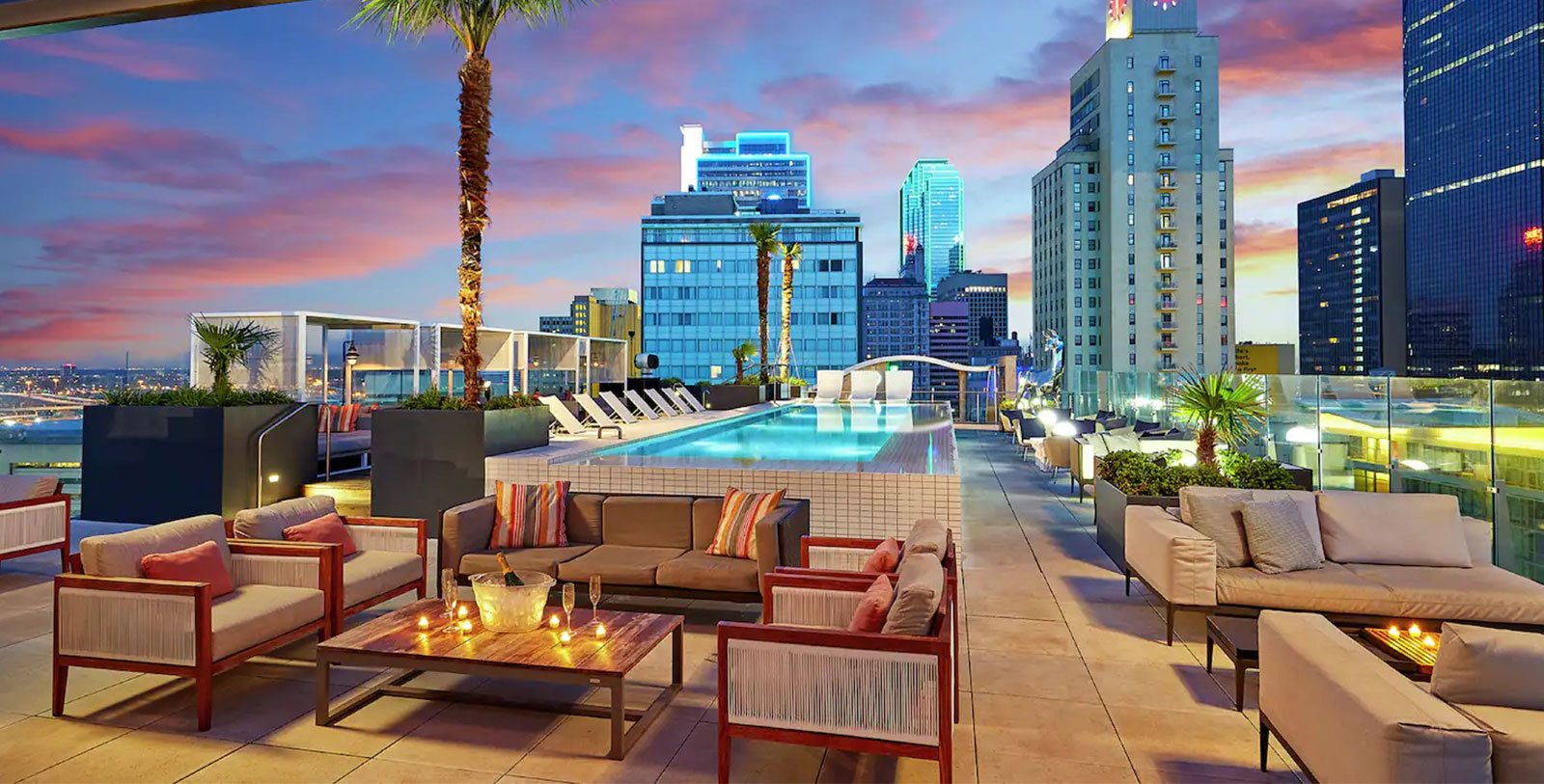 a rooftop pool with chairs and tables and palm trees