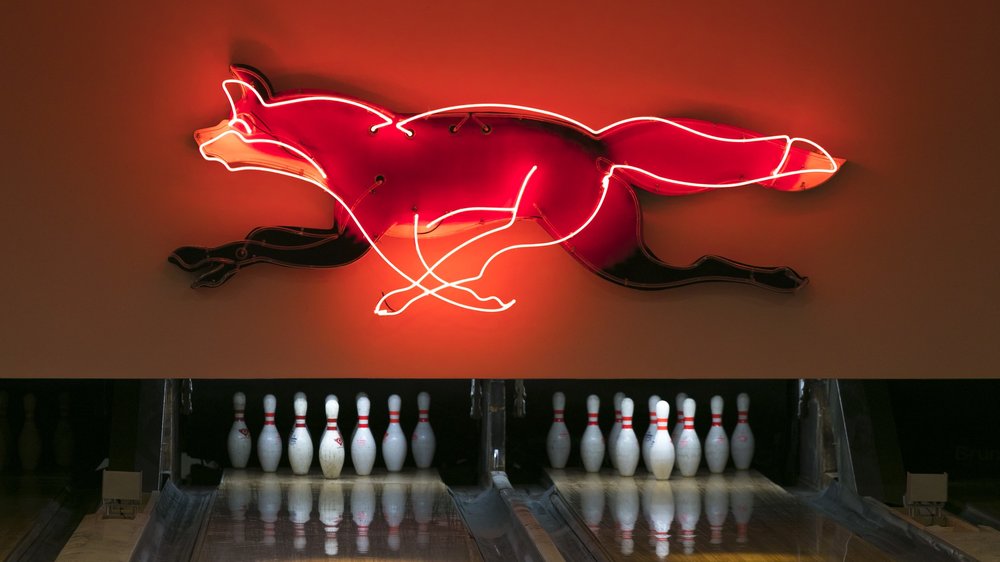 a neon sign with a fox on the wall and bowling pins