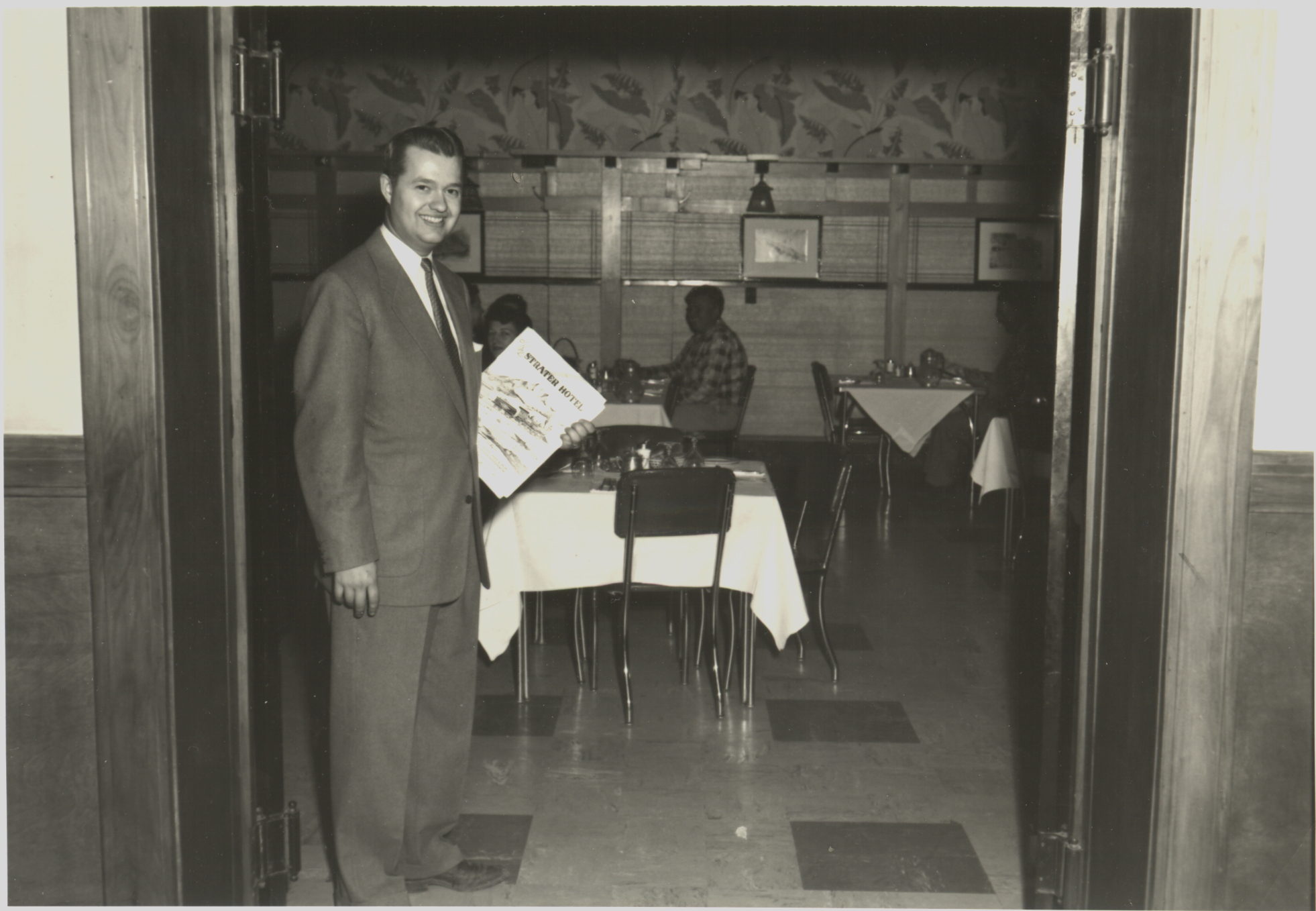 a man standing in a room with a table and chairs