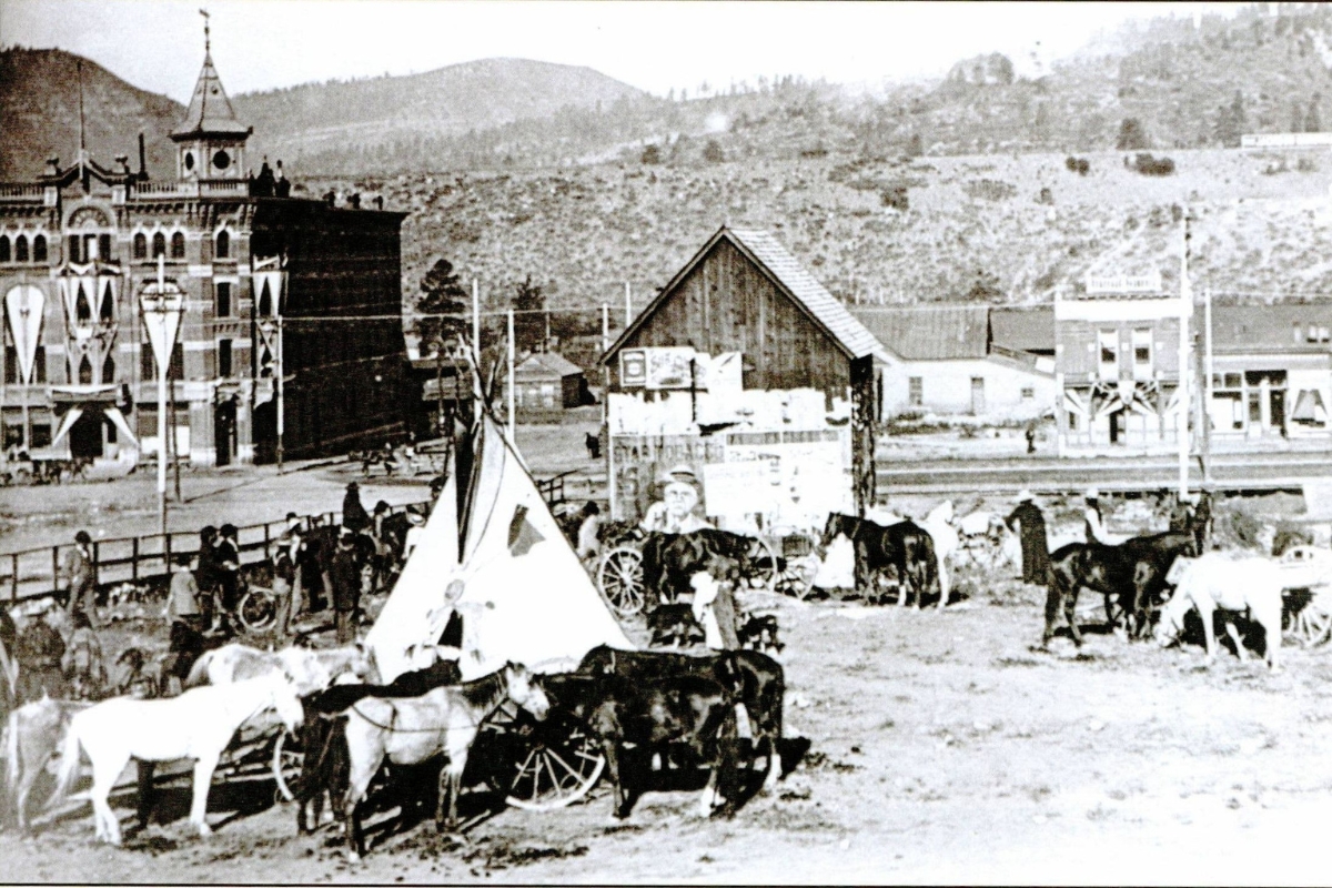 a group of horses and a tent in front of a building