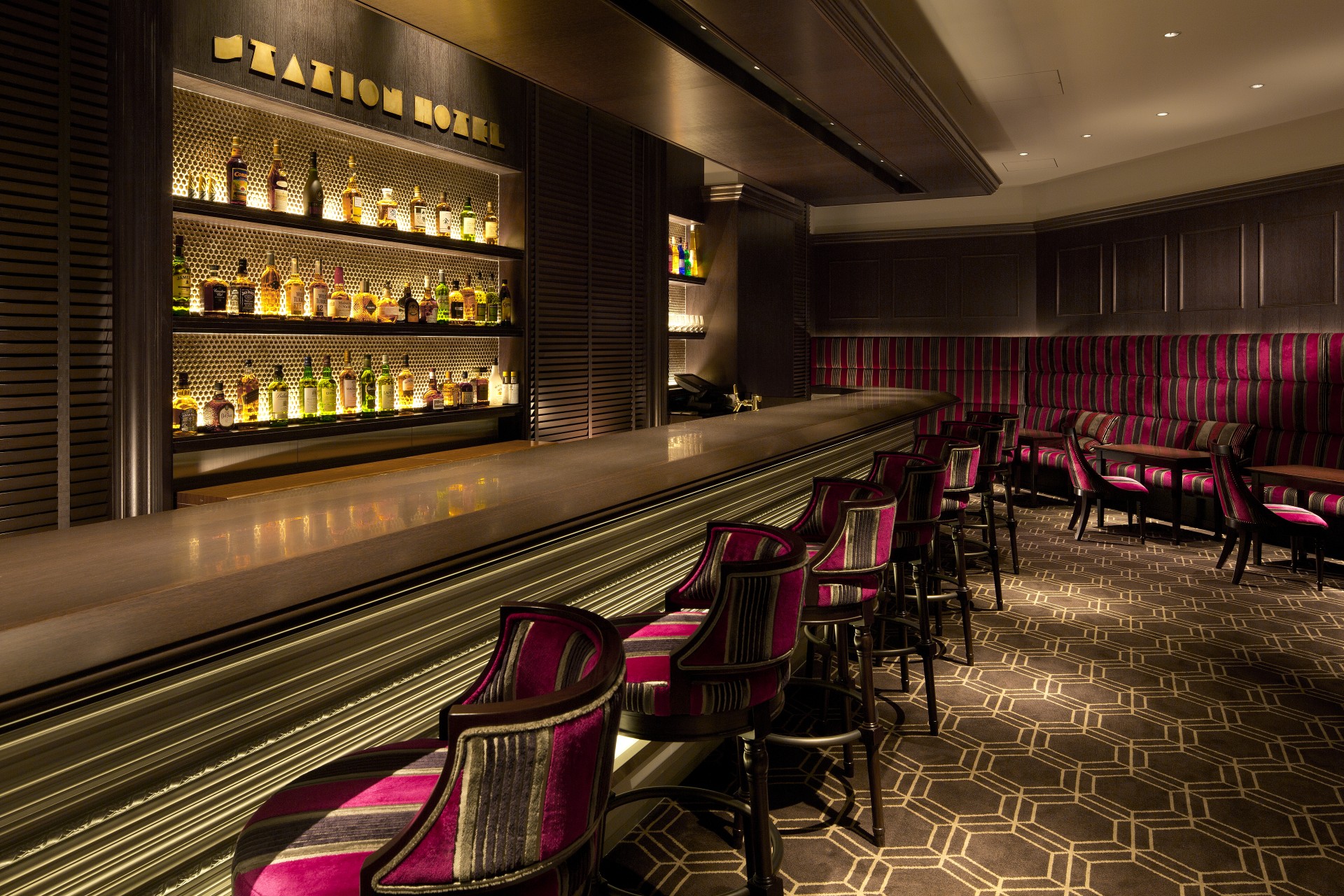 a bar with chairs and a shelf with bottles
