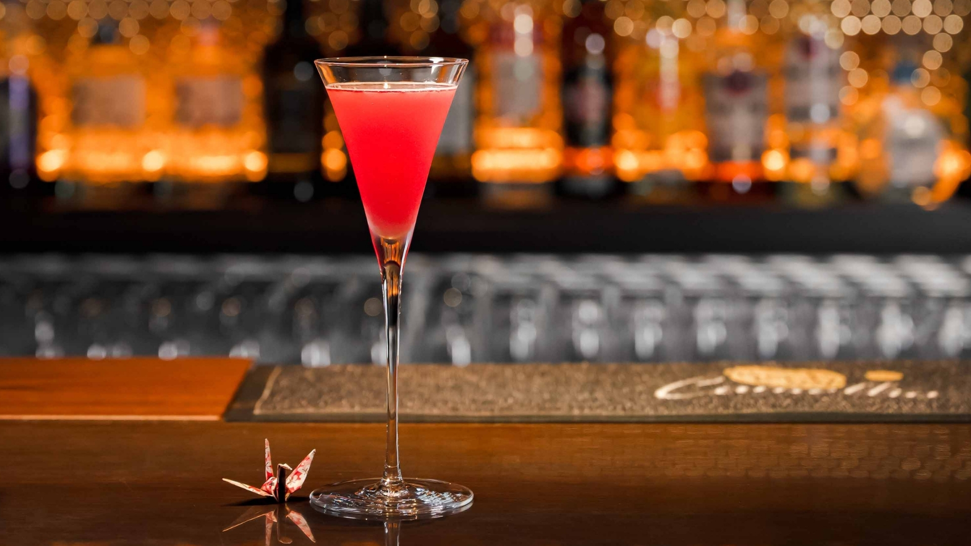 a glass of pink liquid on a bar counter