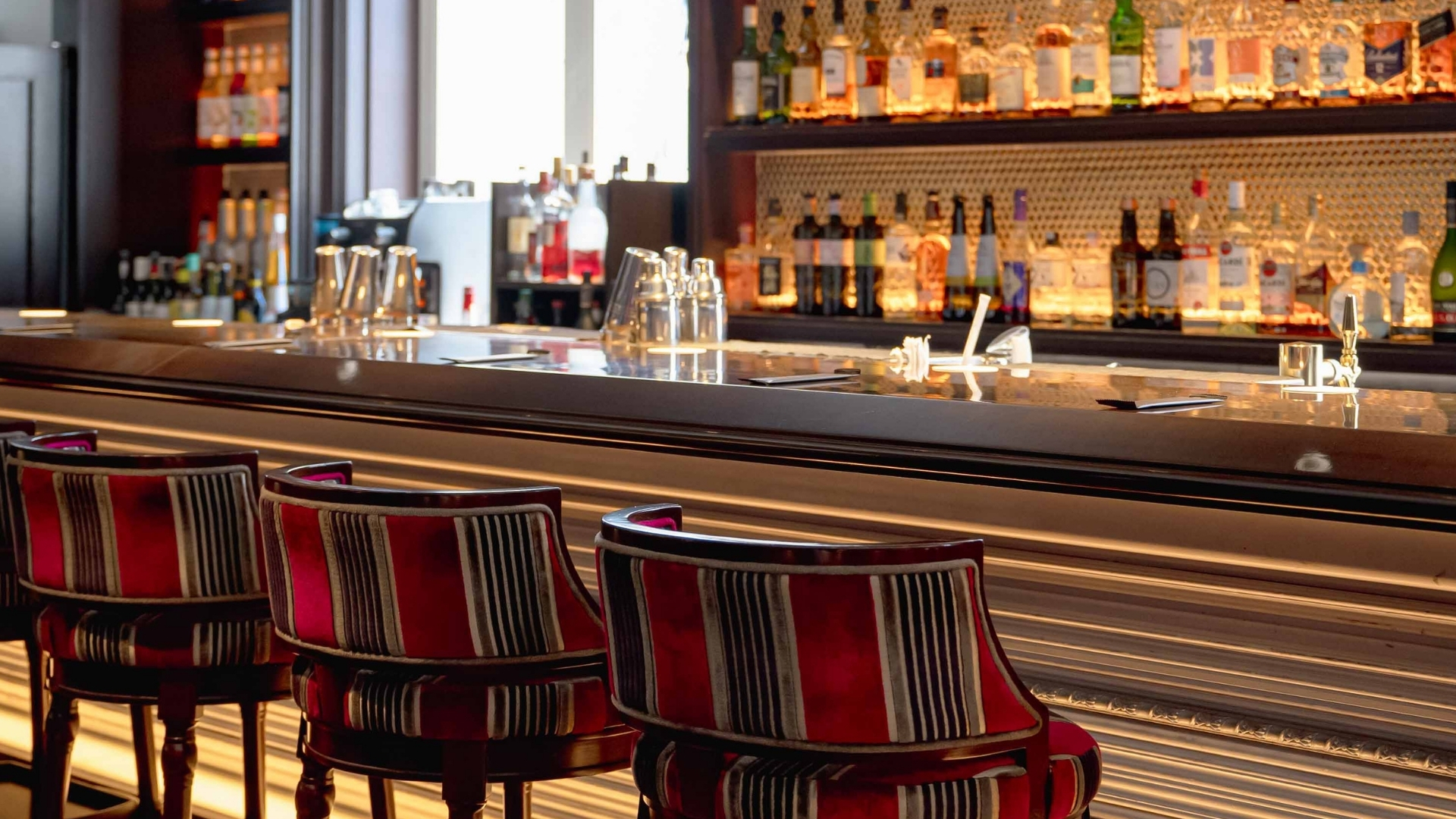 a bar with chairs and bottles of liquor