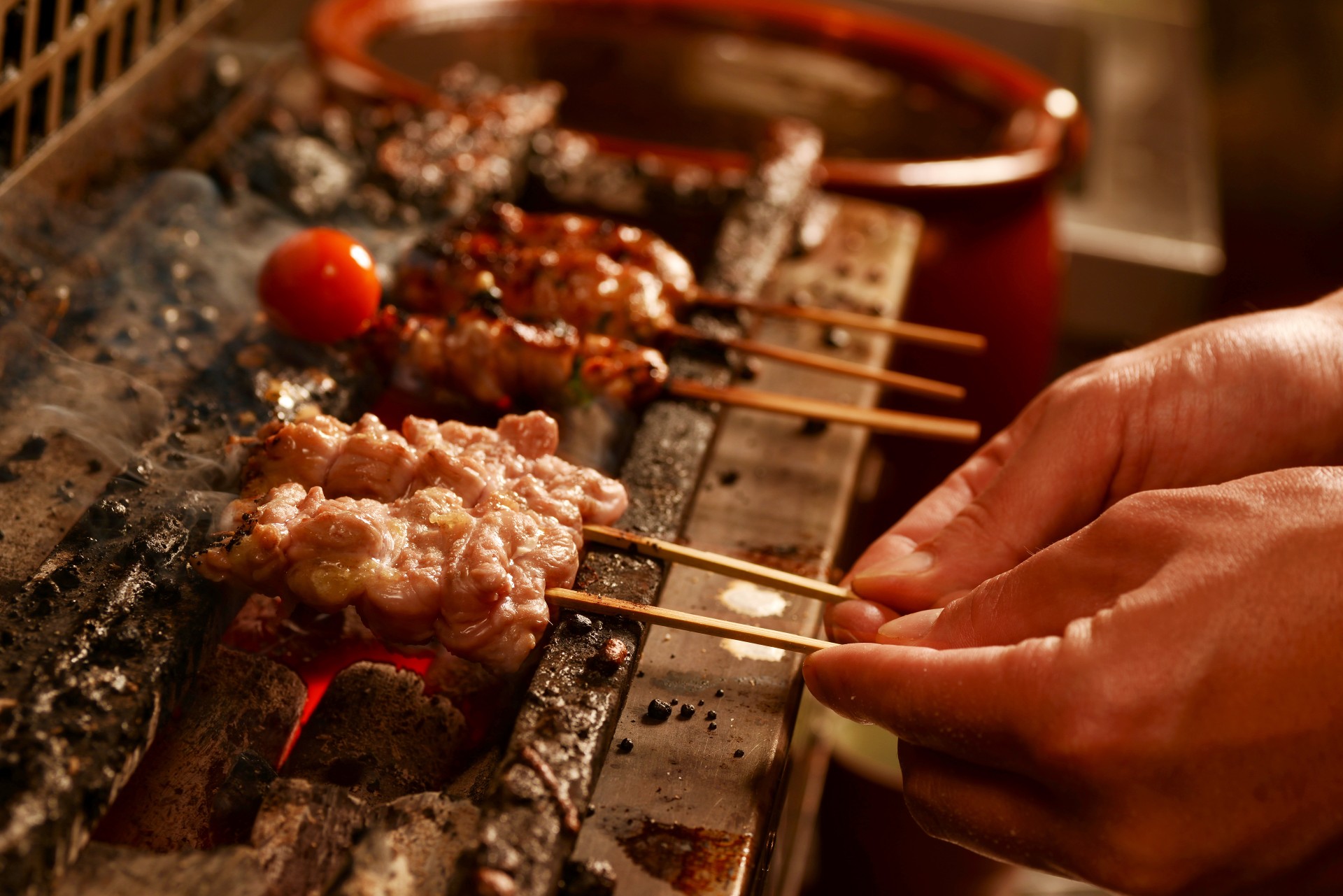 a person holding sticks over food