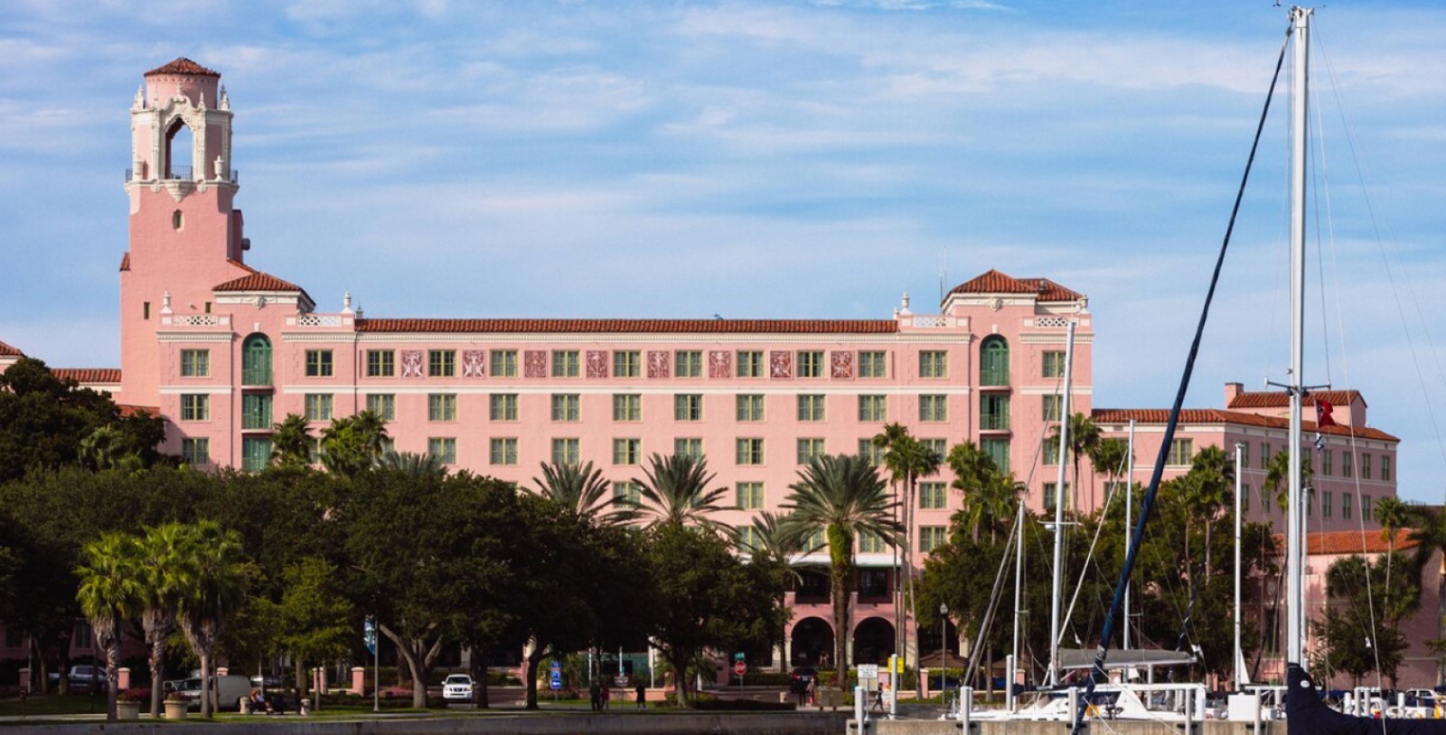 a pink building with palm trees and boats in front