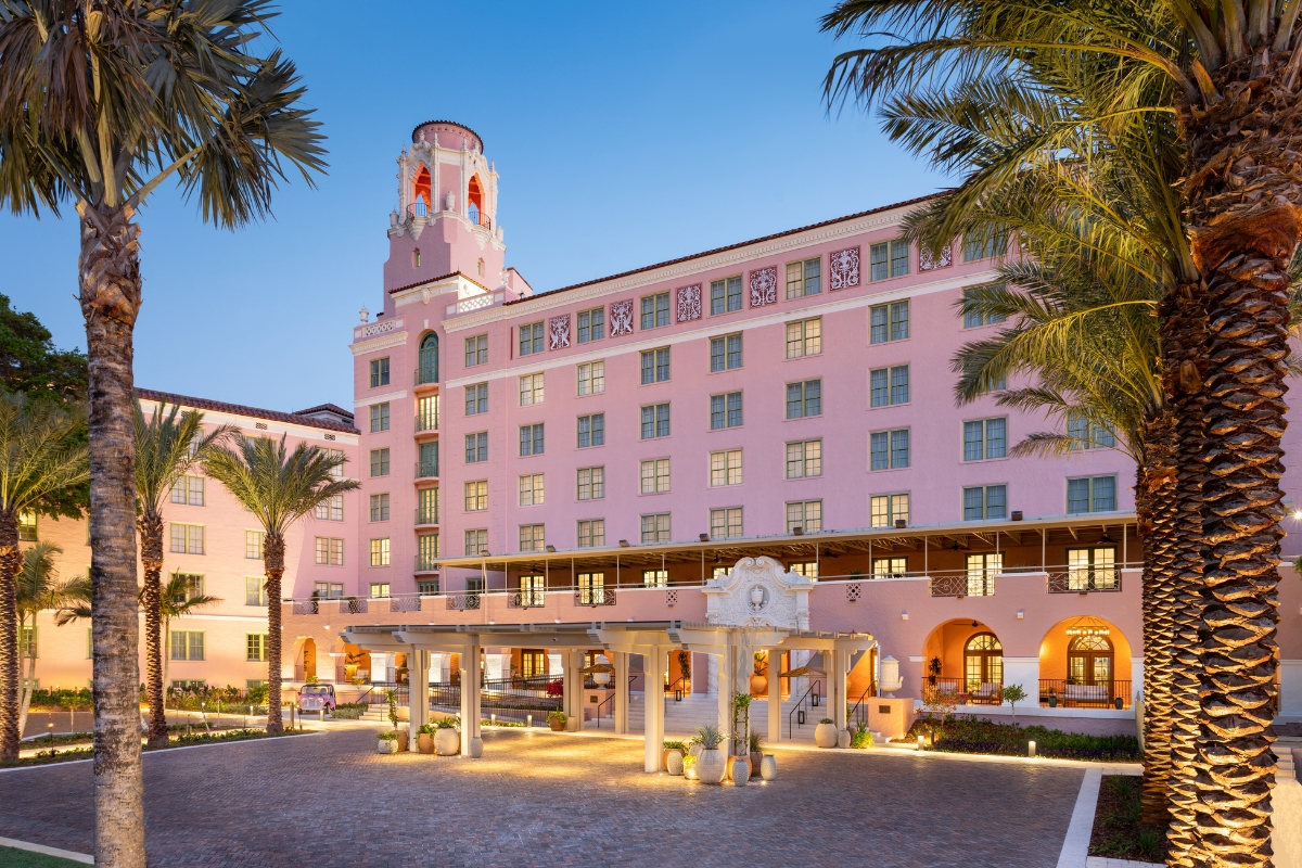 a large pink building with palm trees