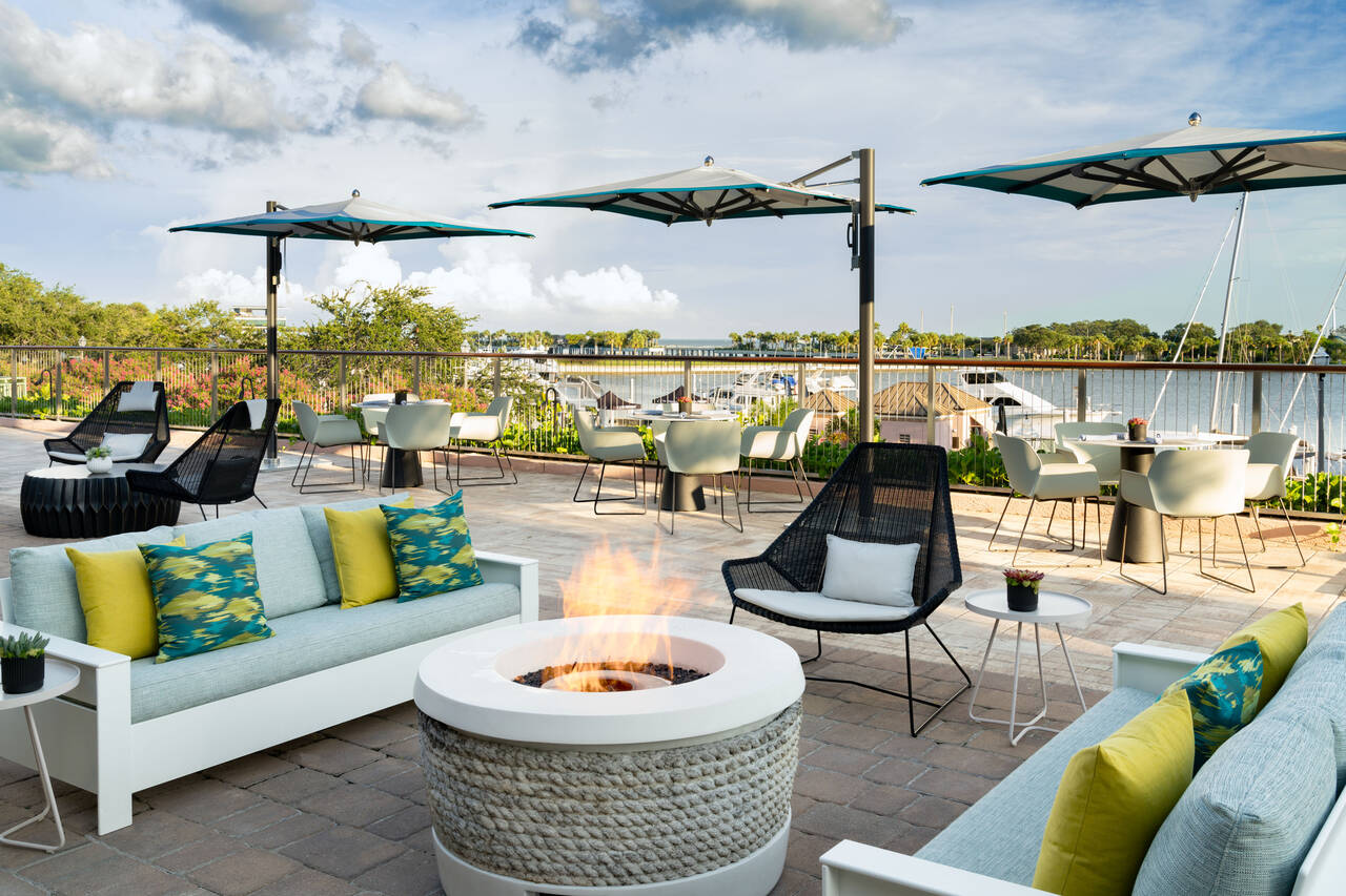 a patio with chairs and umbrellas and a fire pit