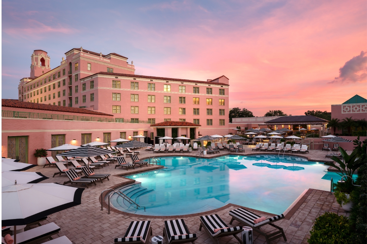 a pool with chairs and umbrellas in front of a building